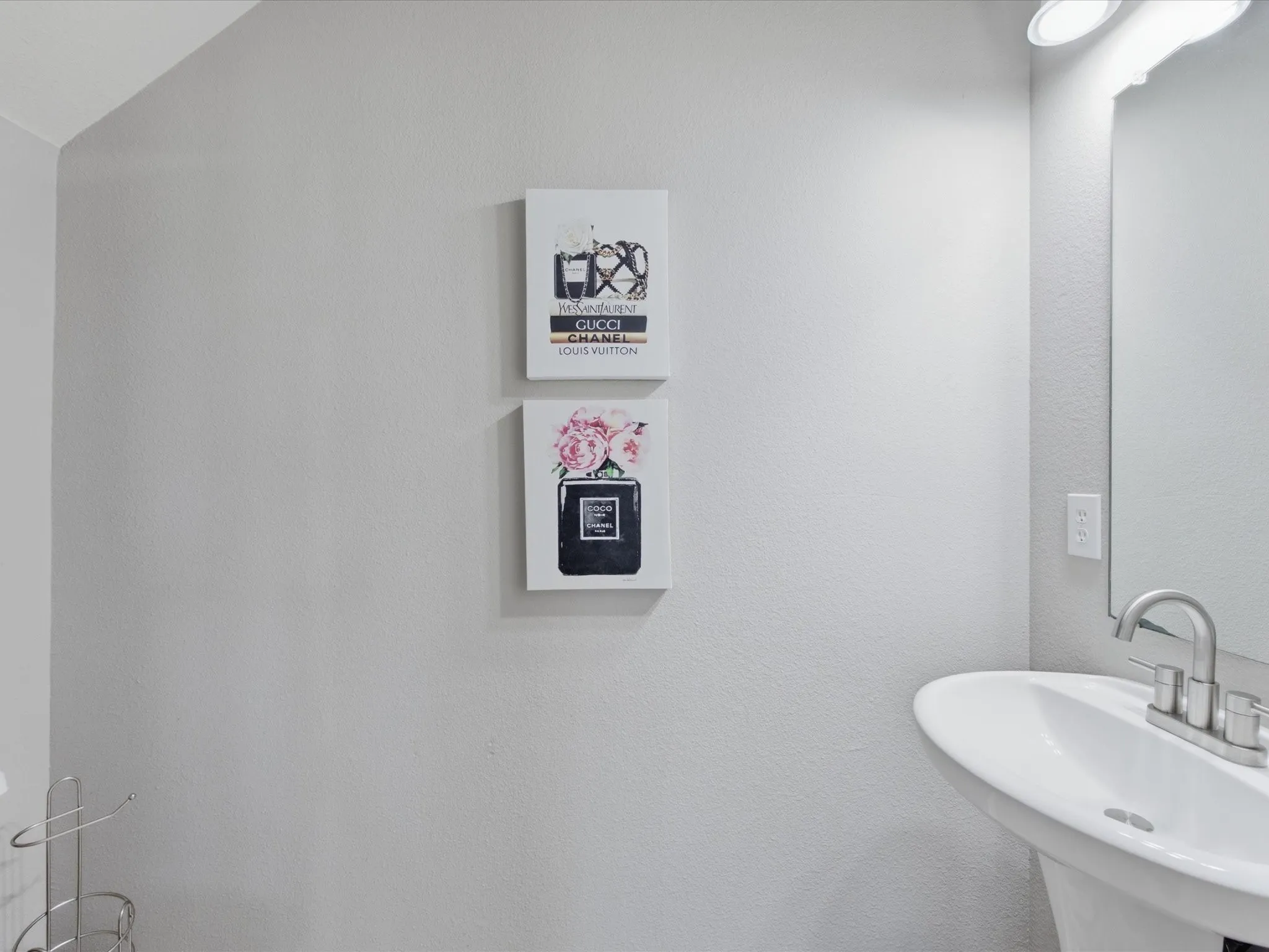 Pedestal sink with chrome faucet, complemented by a wall-mounted mirror and overhead lighting