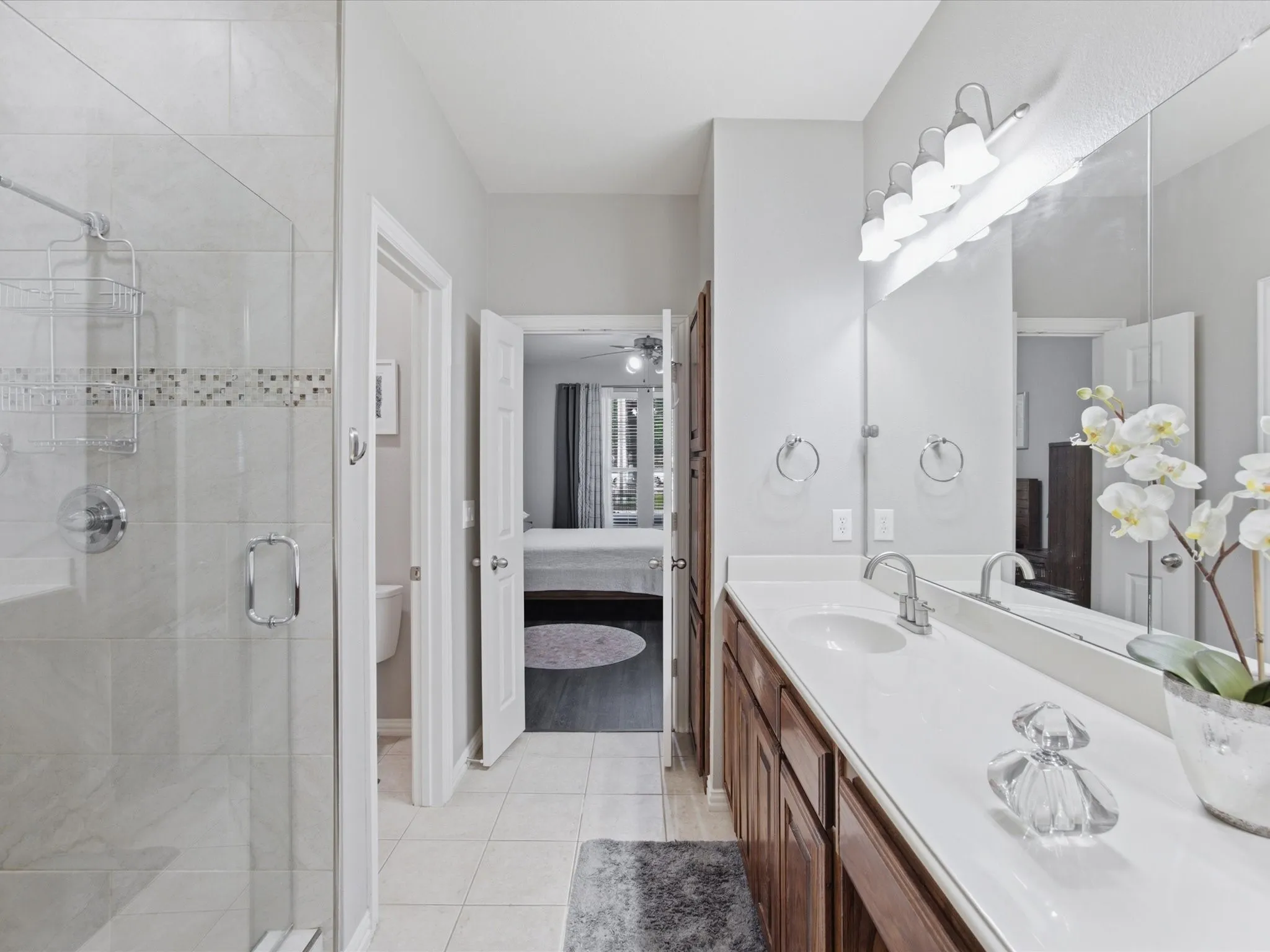 Primary Bathroom featuring a double vanity with stone-finish countertop, wood cabinetry, and a large mirror