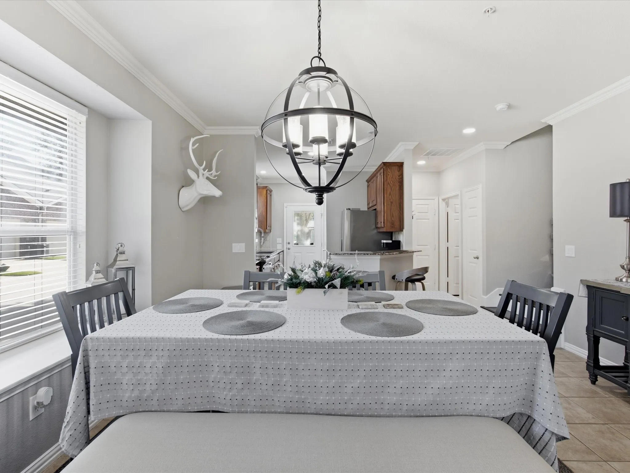 Dining area featuring an open orb chandelier, crown molding, and a window with horizontal blinds