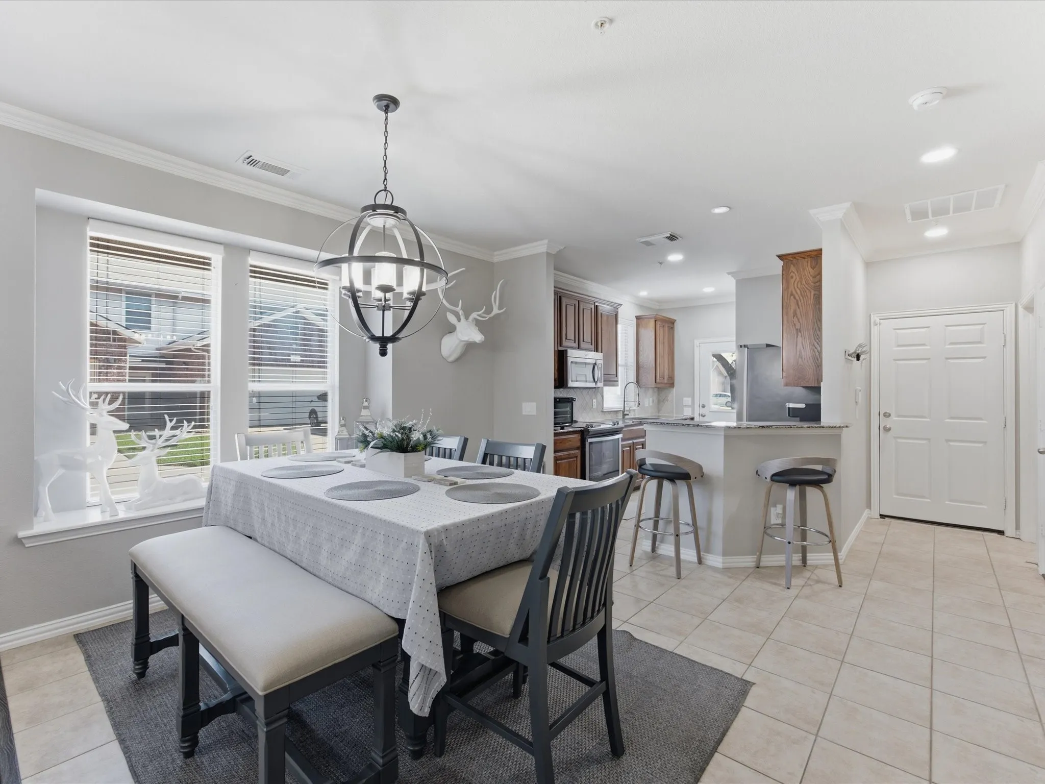 Dining area featuring a contemporary chandelier, two large windows, crown molding, and tiled flooring