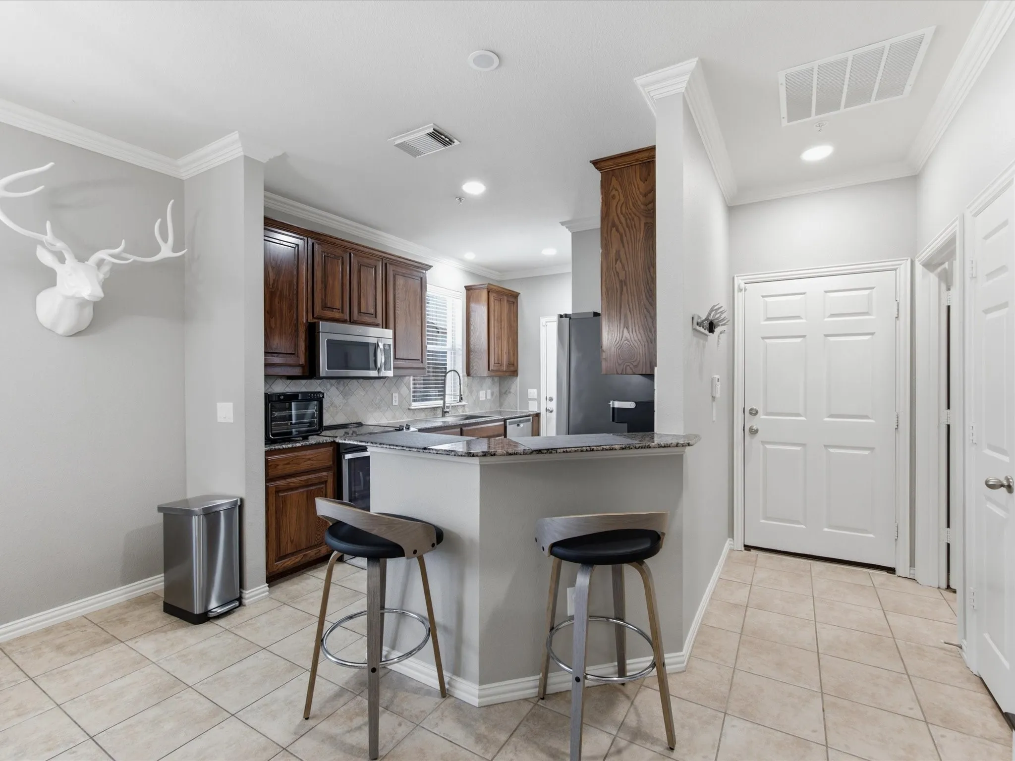 Kitchen with dark wood cabinetry, stainless steel appliances, and a tiled backsplash