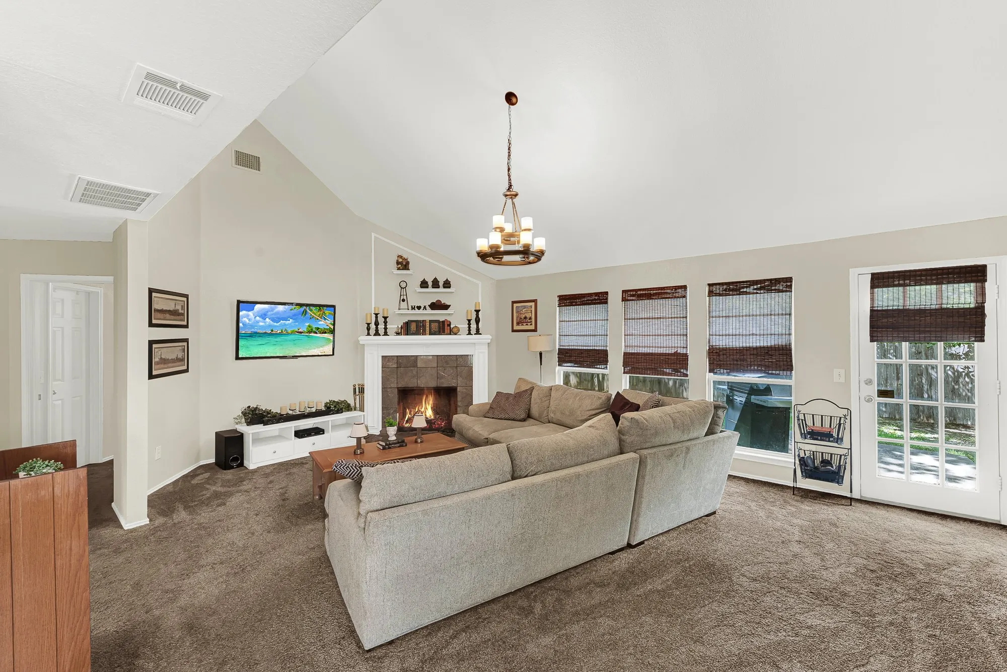 Spacious living area featuring a vaulted ceiling, a tile-surround fireplace with a classic mantel, and an abundance of natural light from multiple windows