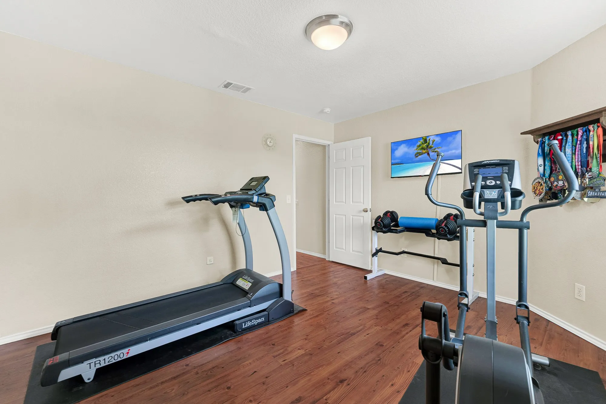 Versatile room featuring wood-finish flooring, neutral wall paint, and a mounted television