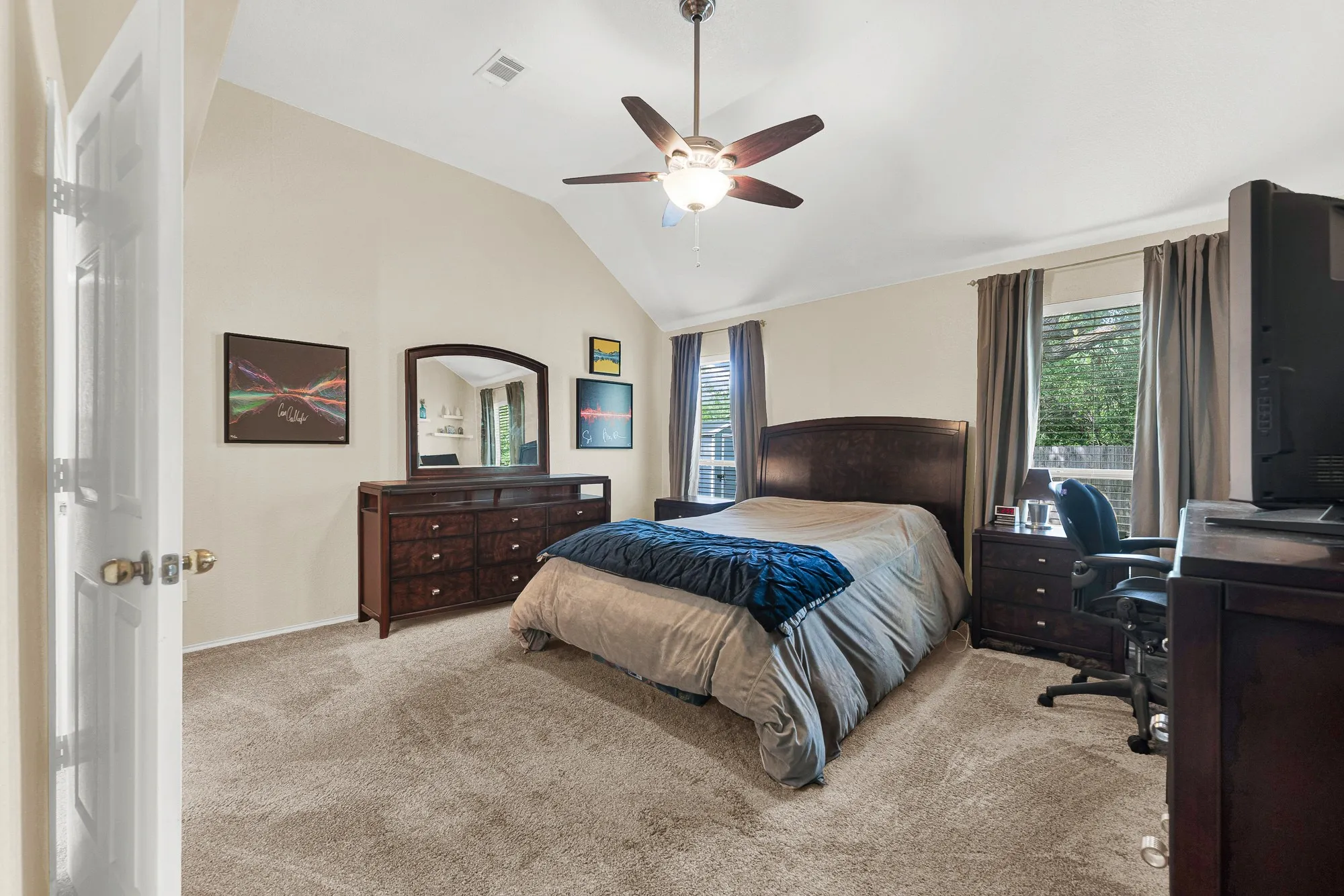 Carpeted room featuring a vaulted ceiling and a ceiling fan with light fixture