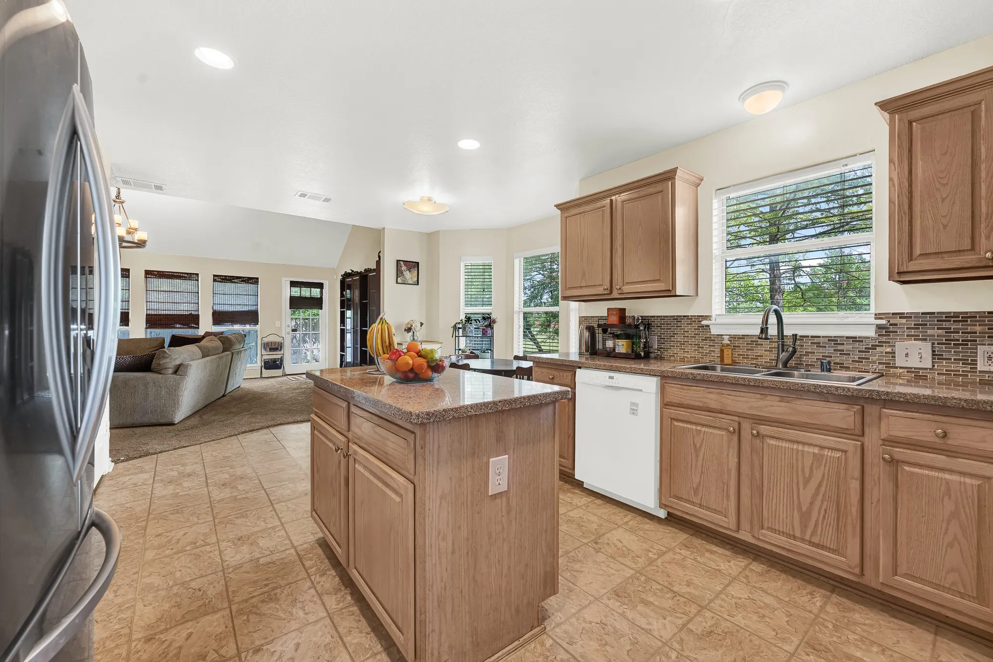 Kitchen featuring a central island, light wood cabinetry, tile flooring, and a patterned tile backsplash