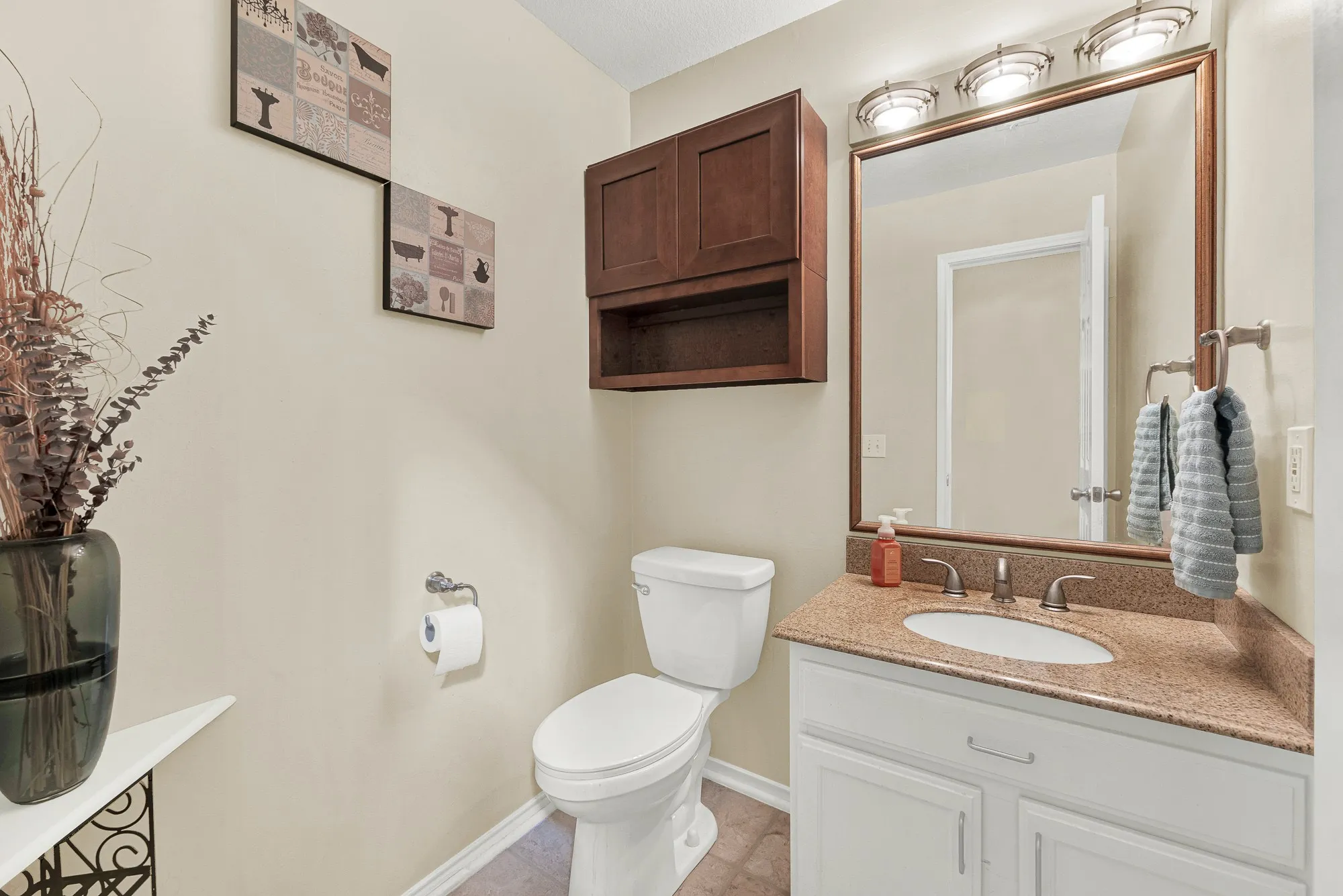 Half-bath next to guest room featuring a white vanity with a built-in sink, speckled countertop, and brushed nickel fixtures