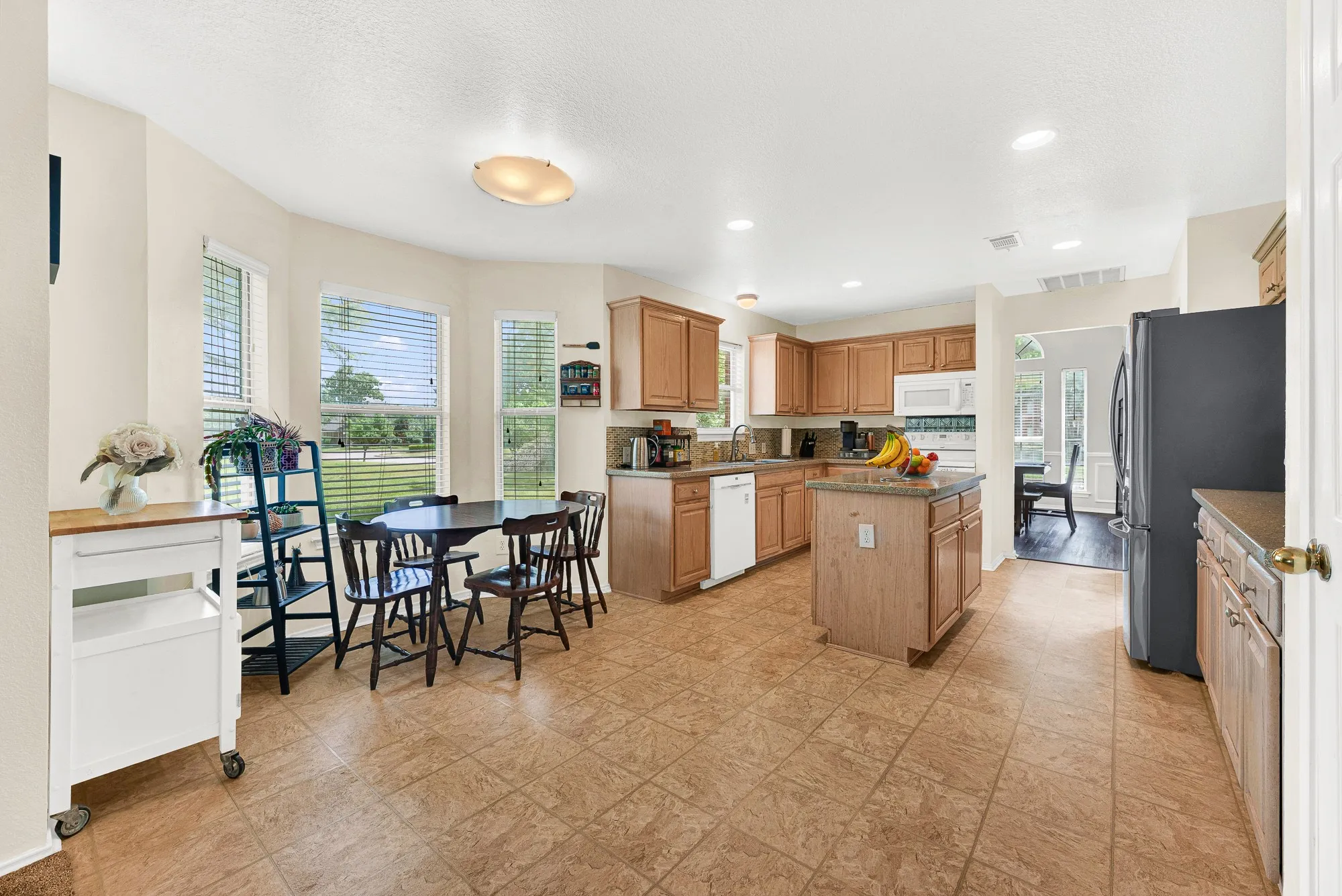 Spacious kitchen featuring tile flooring, light wood cabinetry, a kitchen island, and a built-in microwave
