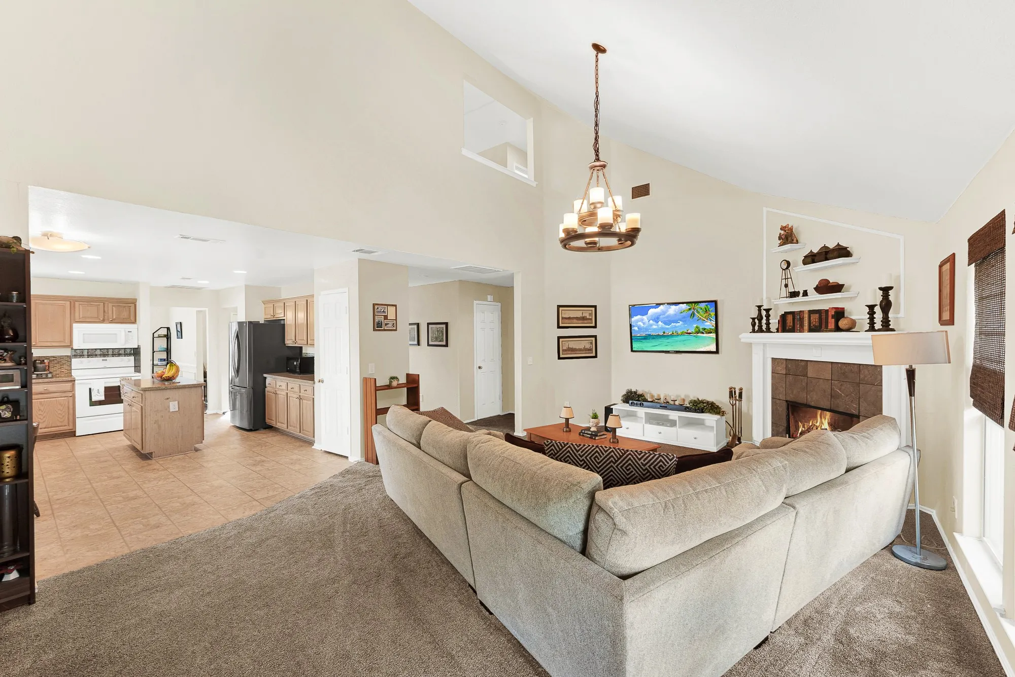 Spacious open-concept living area featuring a vaulted ceiling and an elegant chandelier