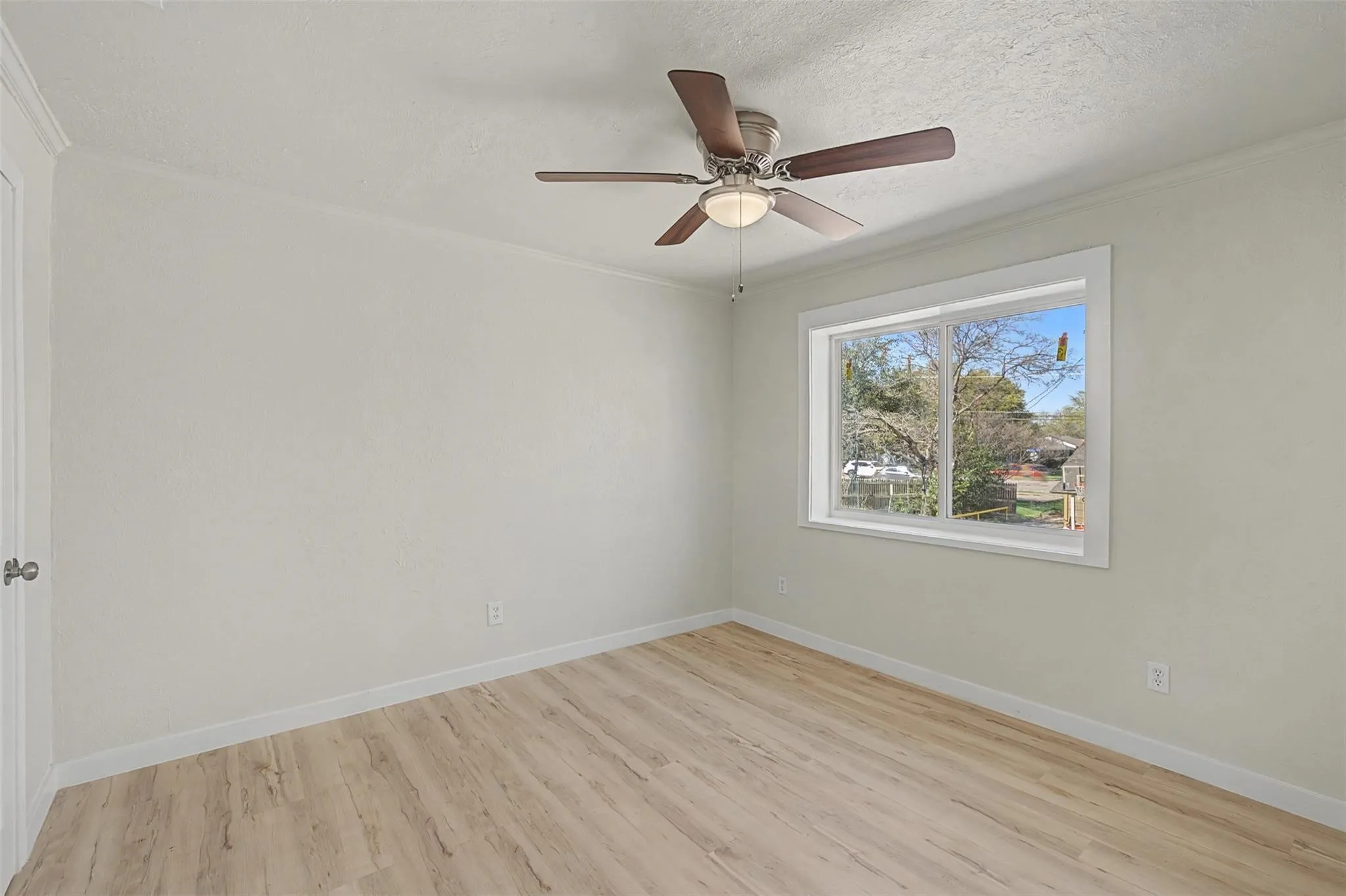 Room with wood-finish flooring, light-toned walls, and a ceiling fan with integrated lighting