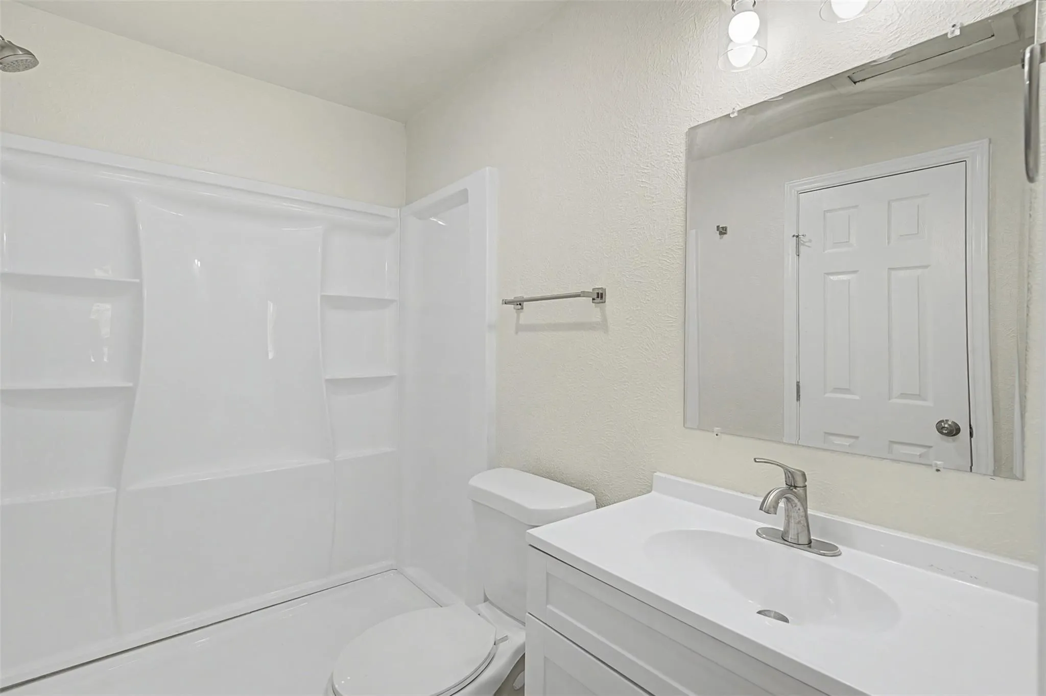 Contemporary bathroom featuring a white vanity with integrated sink, brushed nickel faucet, and an expansive wall-mounted mirror