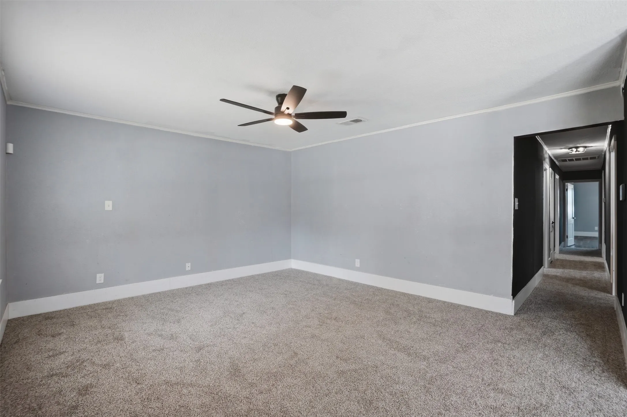 Spacious room featuring light gray walls, white baseboards, and a modern ceiling fan with integrated lighting