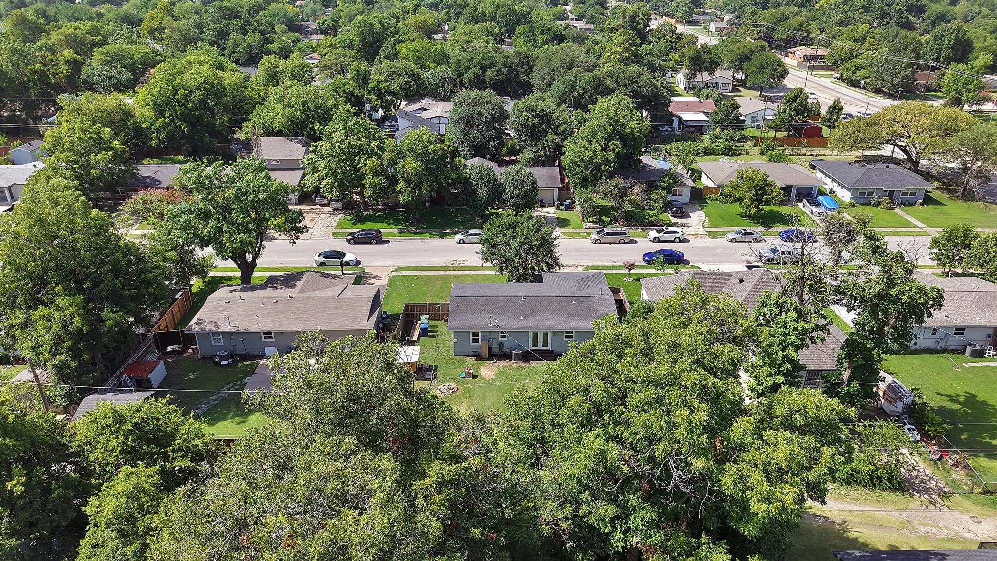 Residential neighborhood featuring mature tree canopy, asphalt streets, and single-story properties