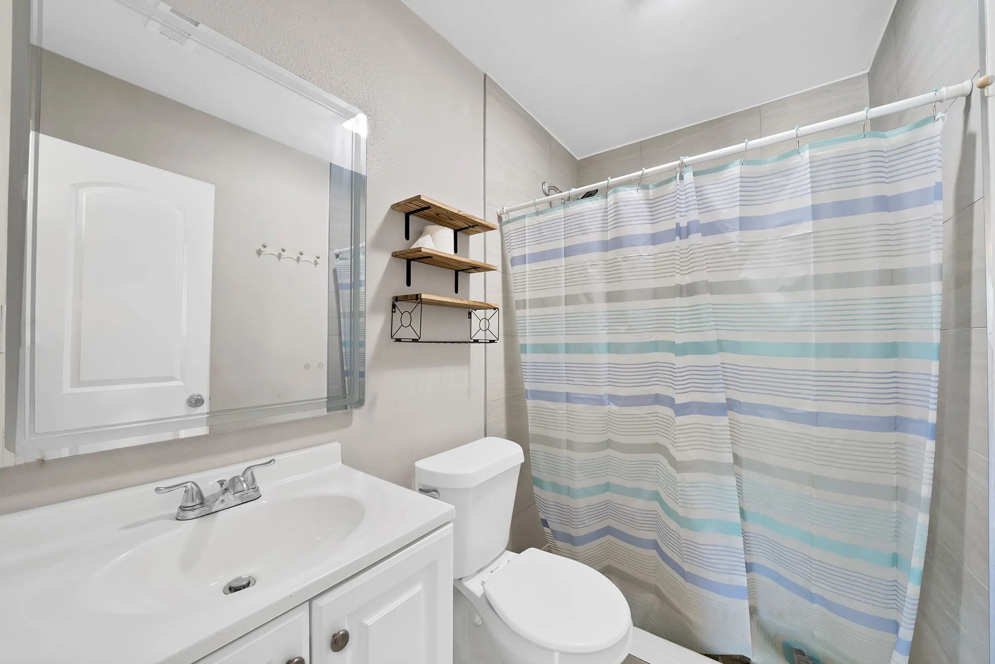Bathroom featuring a white vanity with integrated sink, chrome faucet, and a large mirror