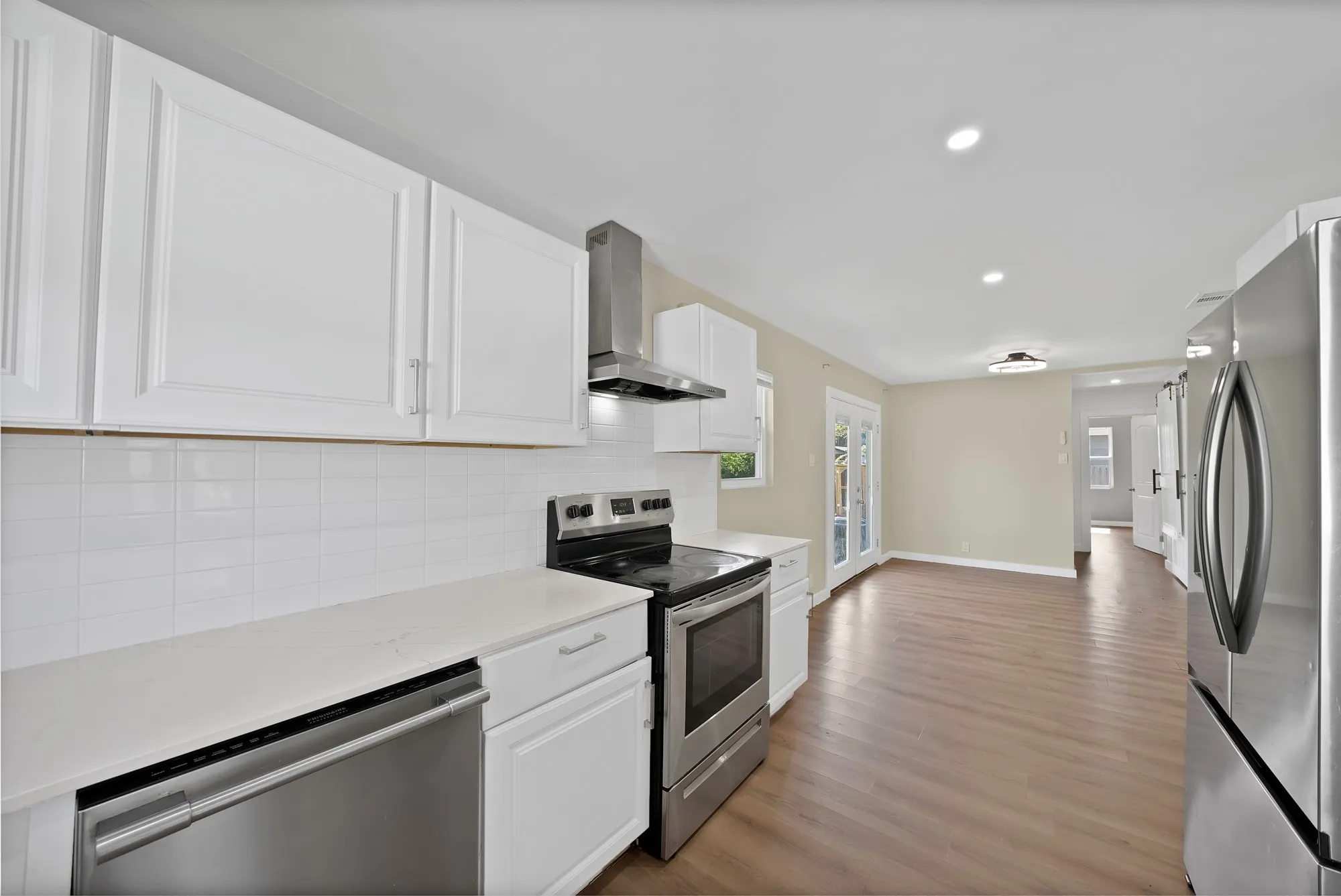 Modern kitchen featuring stainless steel appliances, white cabinetry, a subway tile backsplash, and light countertops