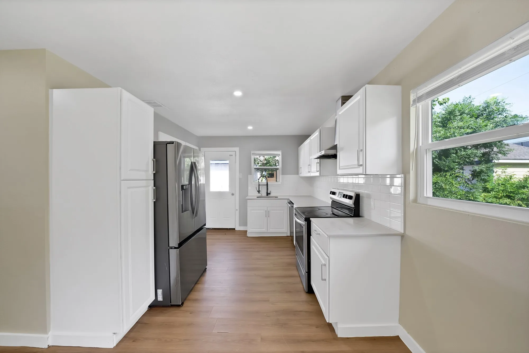 Kitchen featuring white cabinetry, wood-finish flooring, recessed lighting, and a subway tile backsplash