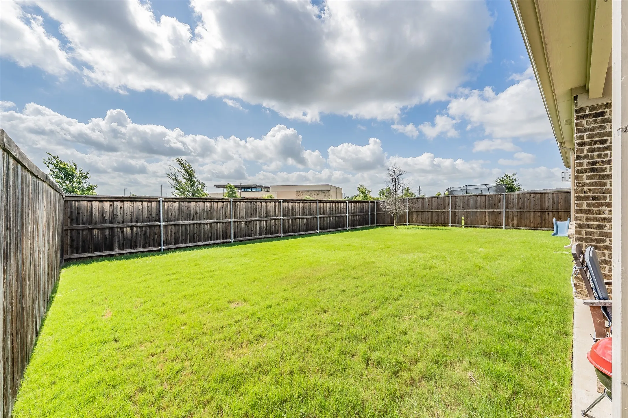 Private backyard featuring a manicured lawn, full wood fencing, and a concrete patio area. Enjoy privacy with open field behind home.