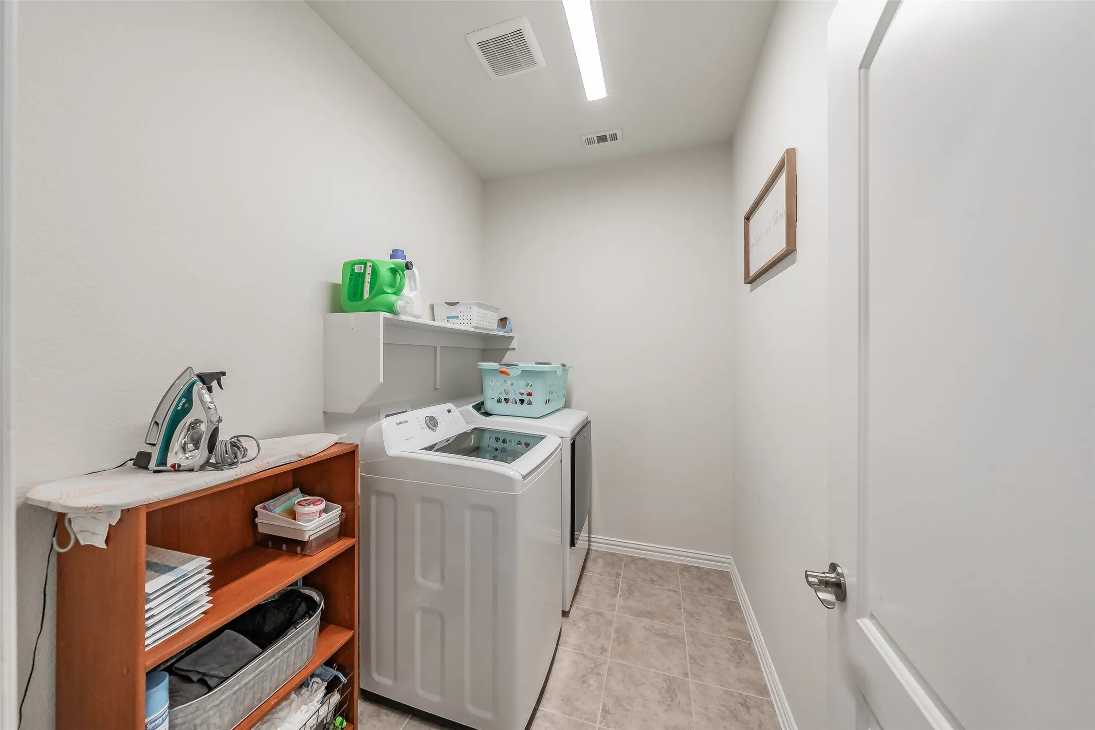 Dedicated laundry area featuring tile flooring with room for cleaning supplies or deep freeze