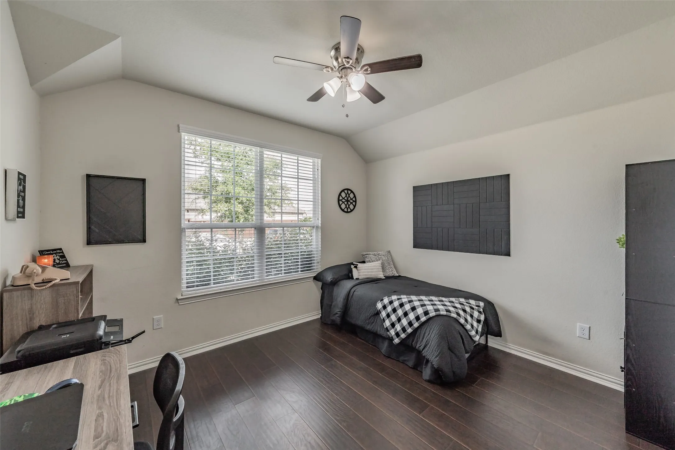 Bedroom featuring vaulted ceilings, a large window with white blinds, dark laminate wood flooring, and ceiling fan