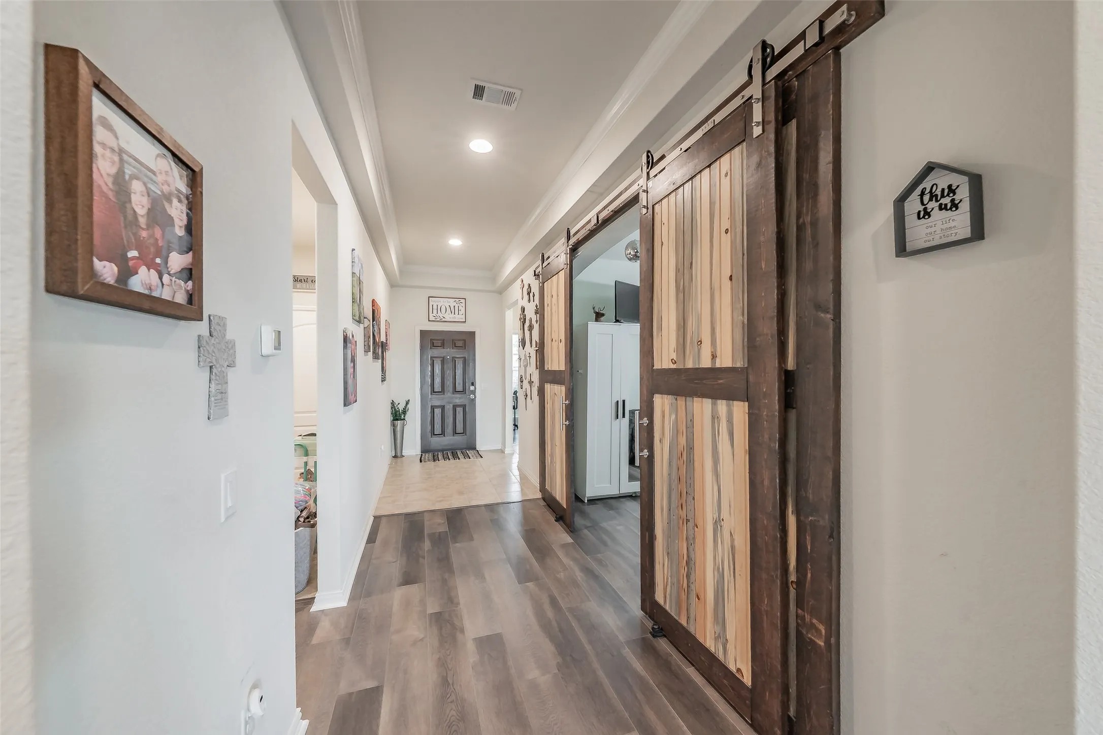 Foyer, featuring ceramic tile entry and laminate wood flooring, two-tone custom barn doors to dinning room or flex space, second living, or office space-so many options!  Elegant tray ceiling and recess lighting
