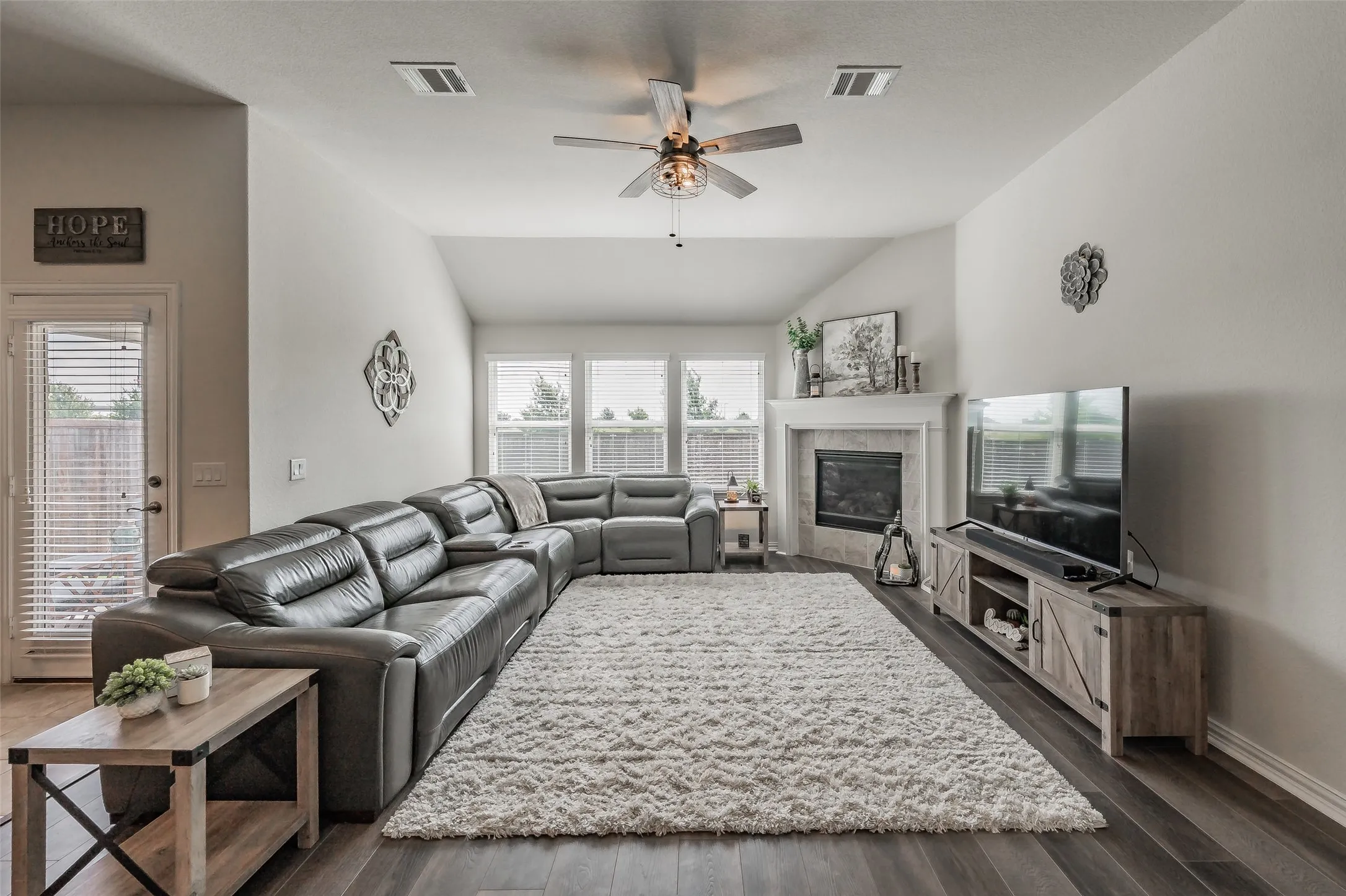 Spacious living area featuring high vaulted ceilings, laminate wood flooring, corner fireplace with natural lightining