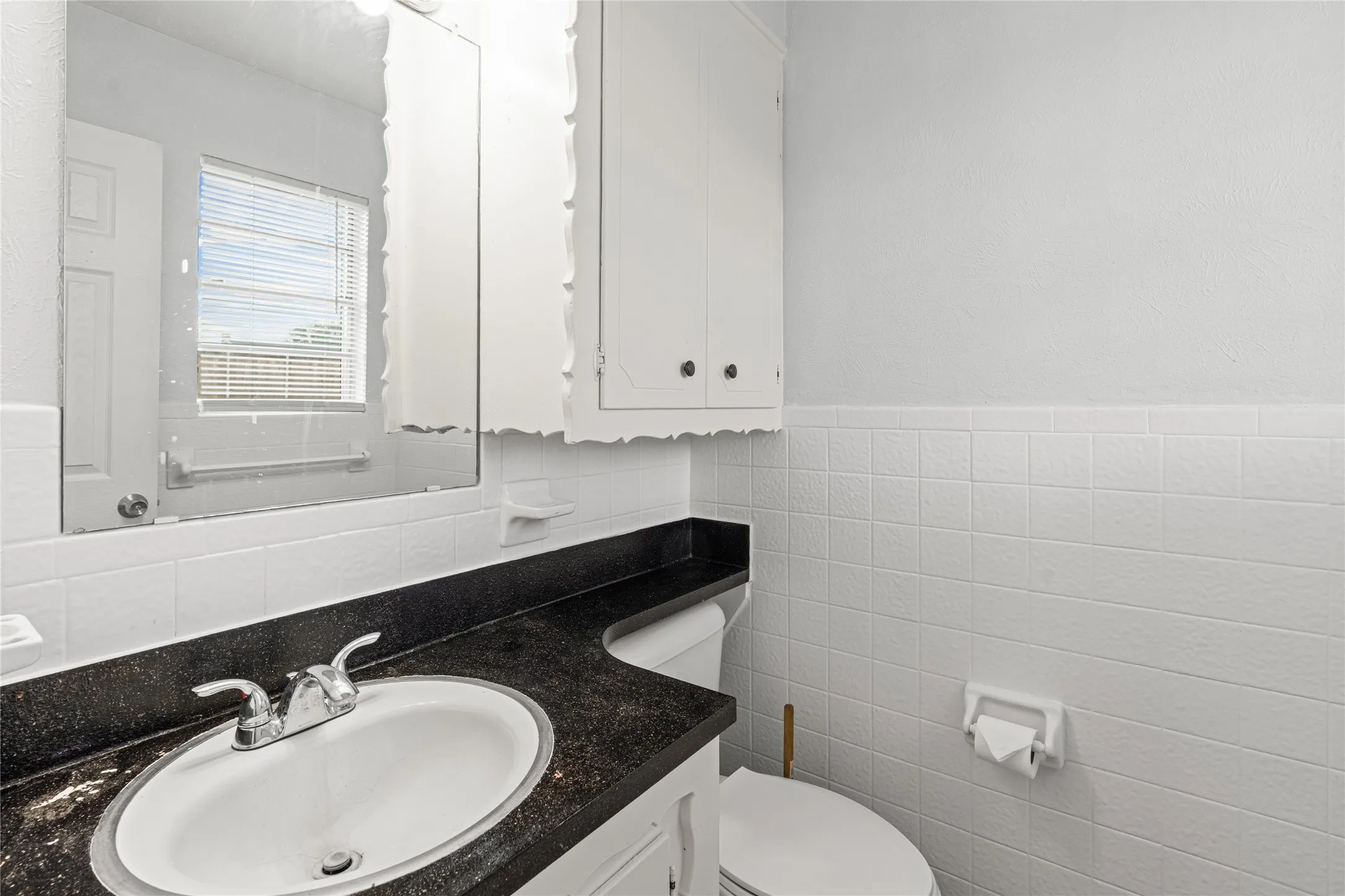 Bathroom featuring a vanity with an integrated sink, dark countertop, and chrome faucet
