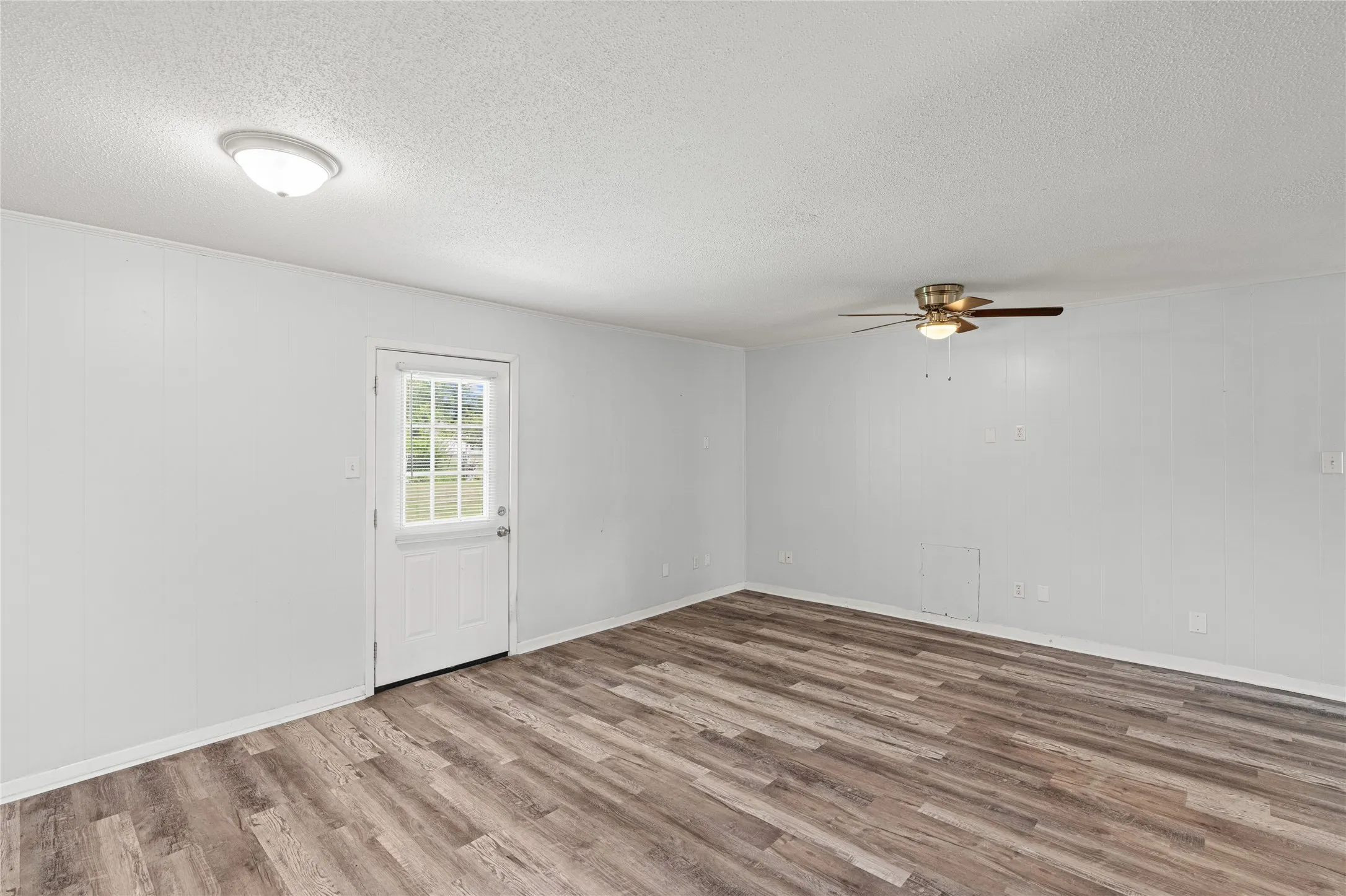 Spacious room featuring wood-finish flooring and white walls