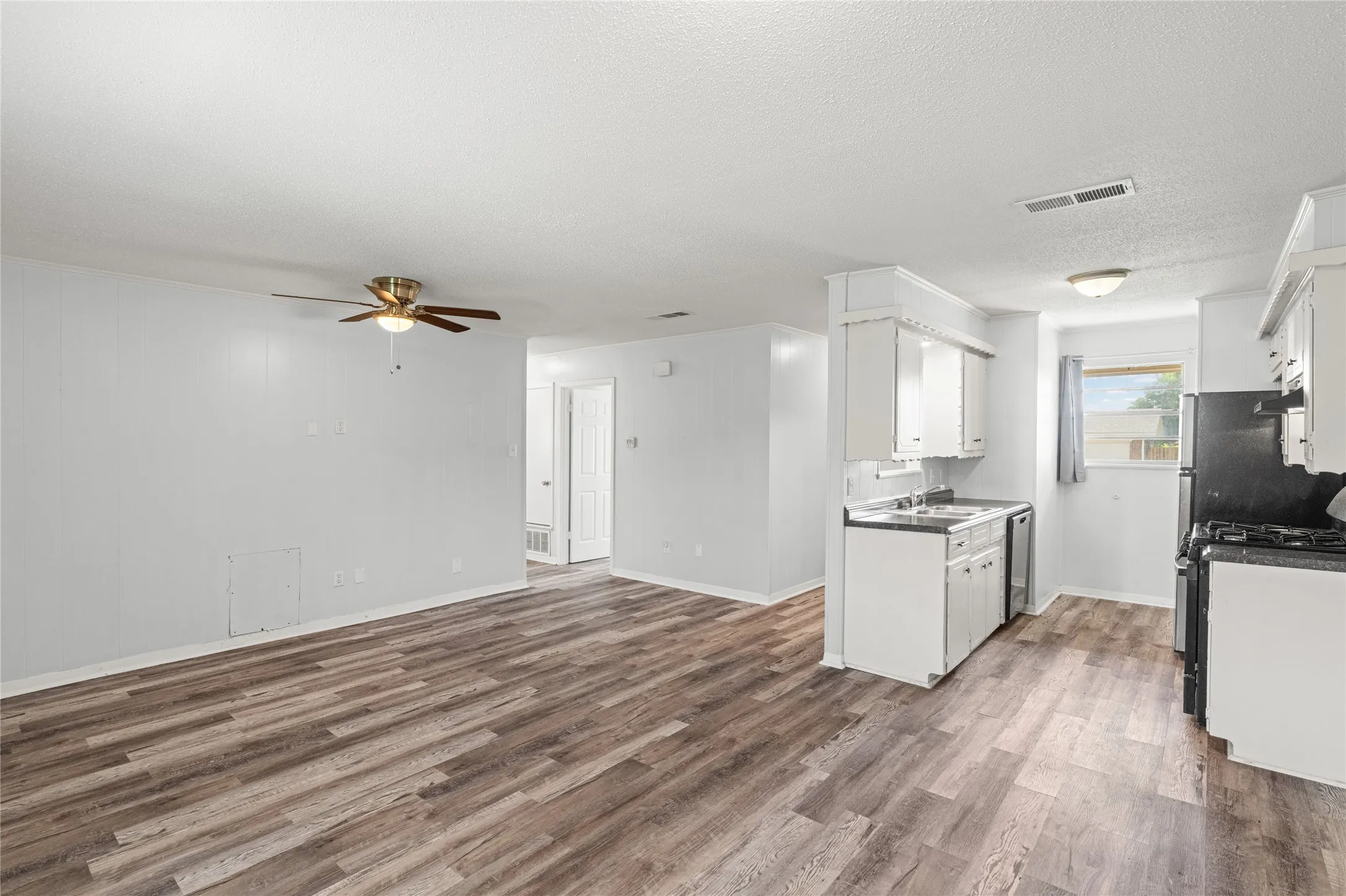 Open-concept living area featuring wood-finish flooring and a ceiling fan
