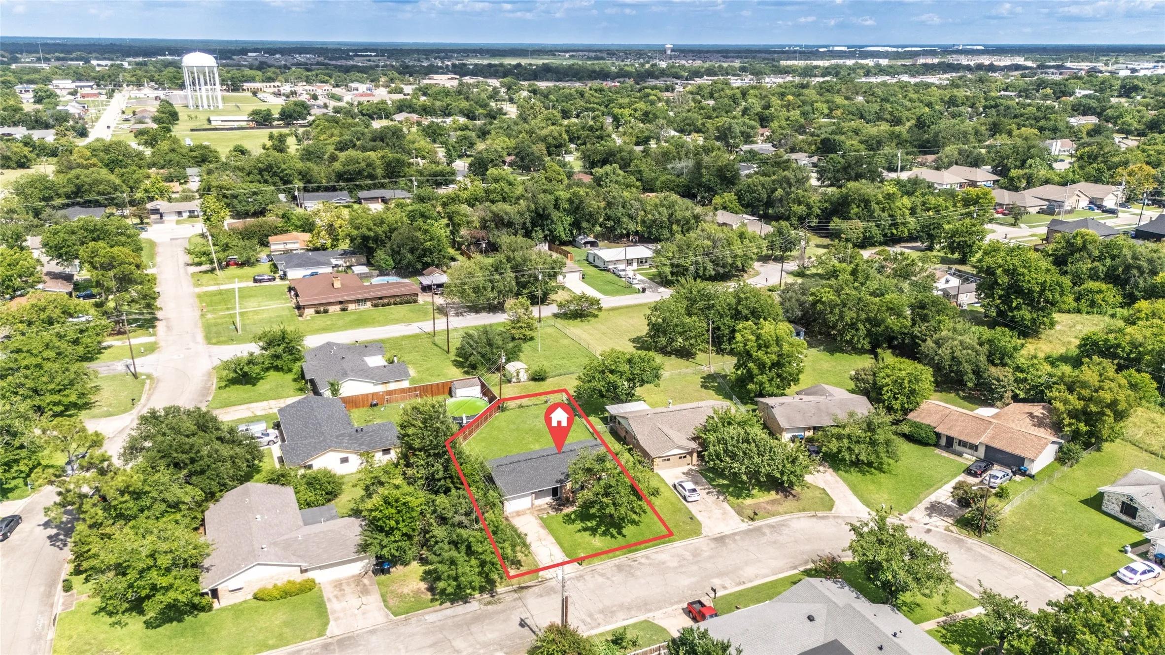 Aerial perspective highlighting a single-story residence with a dark shingle roof and a concrete driveway