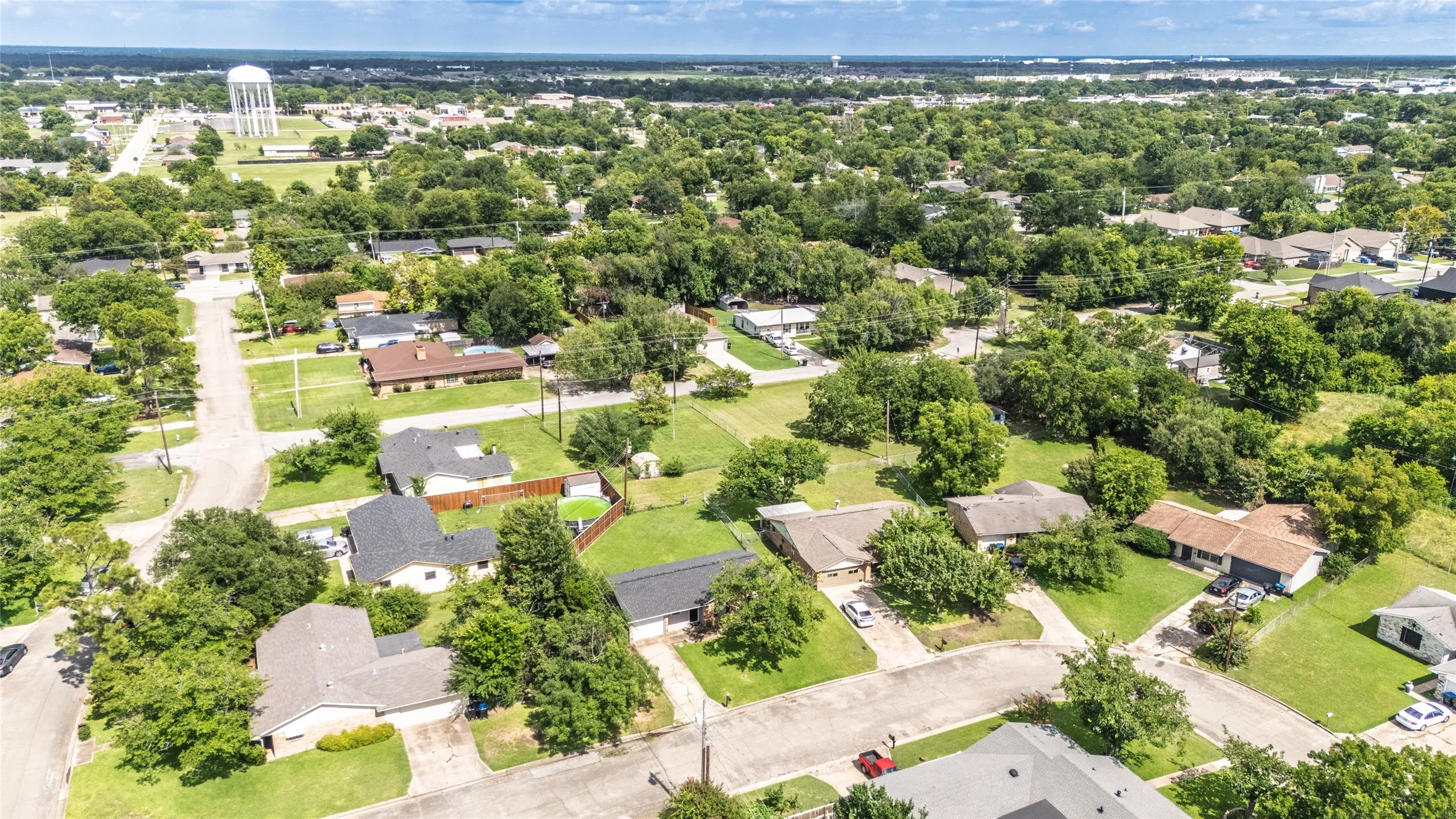 Expansive residential area featuring numerous mature trees and a water tower in the distance