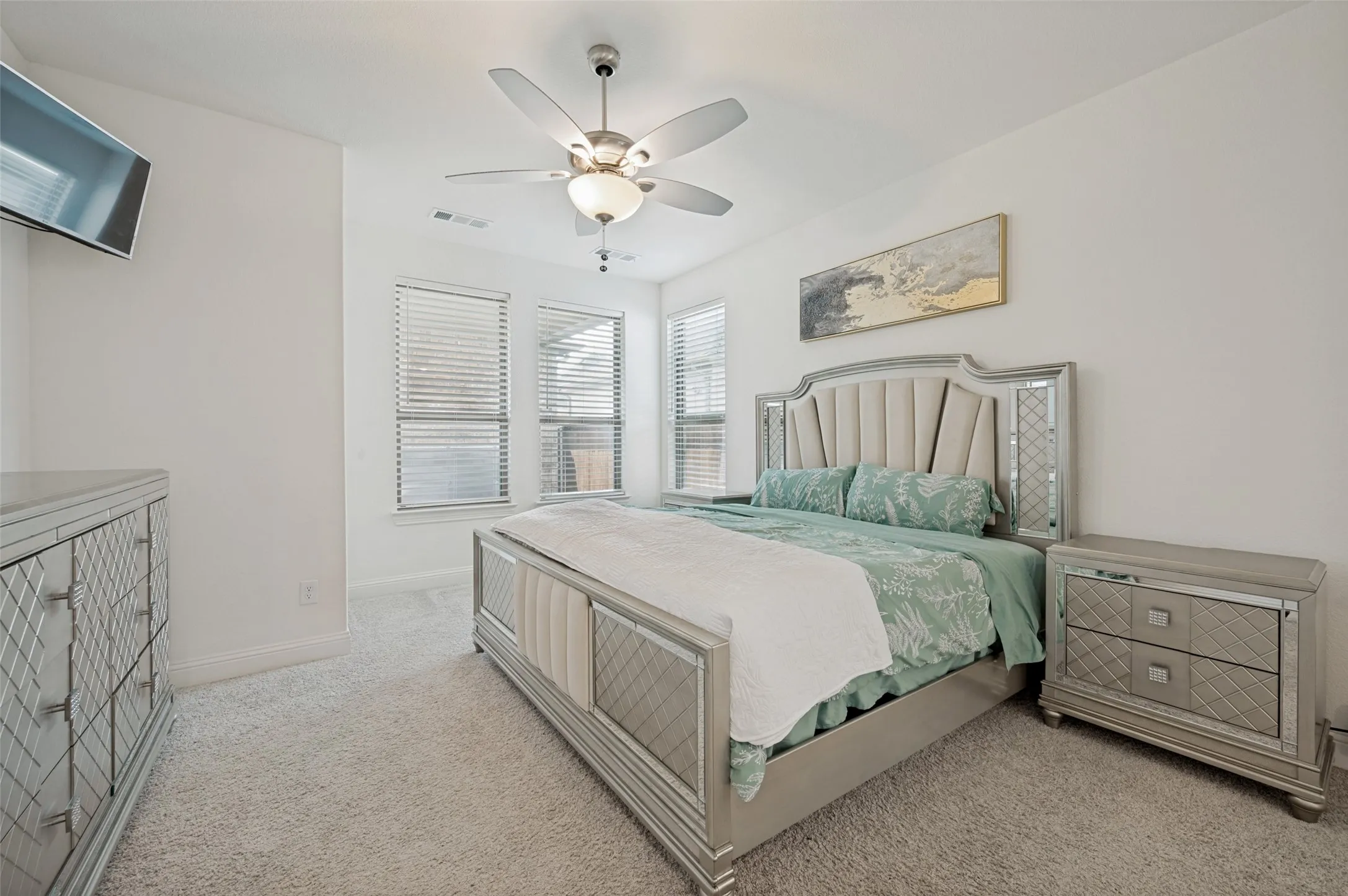 Primary bedroom with ceiling fan and large windows