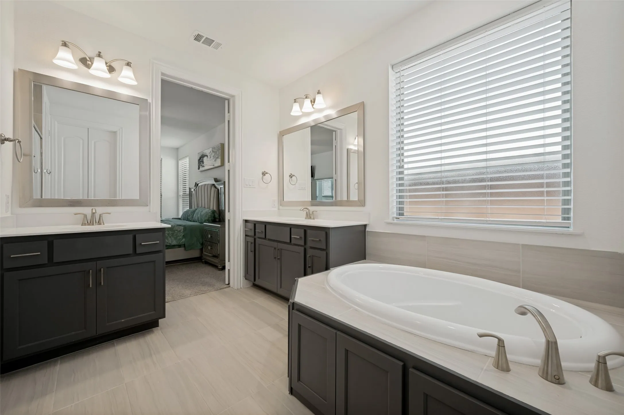 Large primary bath complete with dual vanities, soaking tub, and water closet