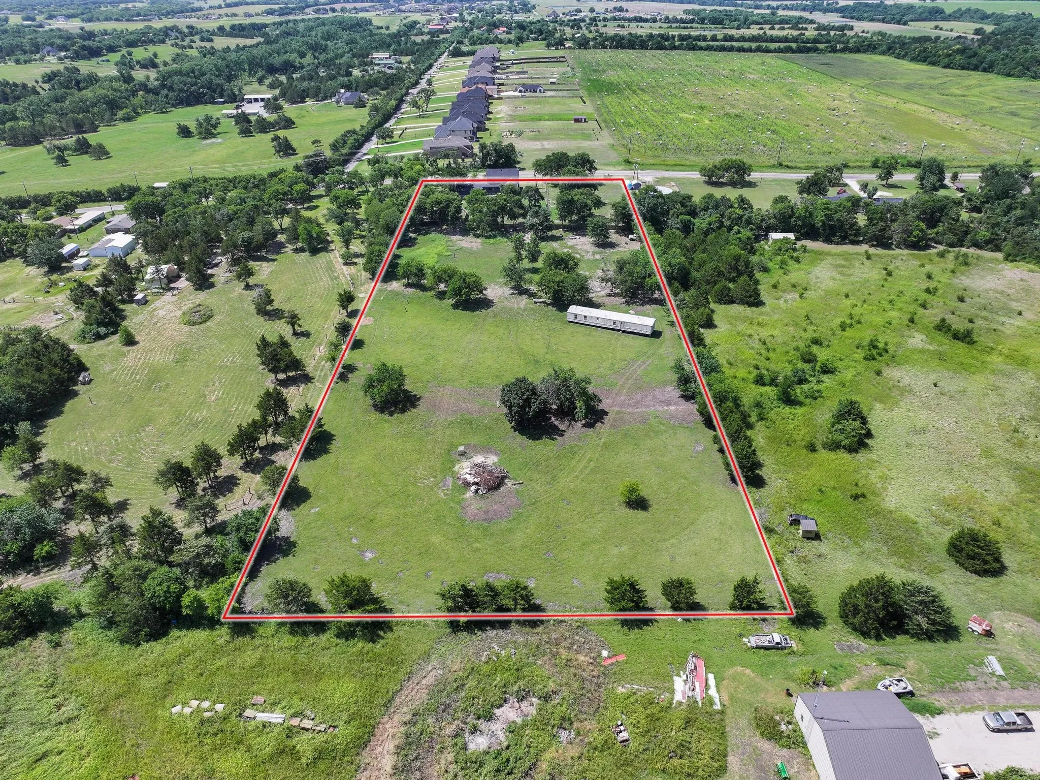 Expansive parcel featuring a large grassy area, mature trees, and a rectangular boundary