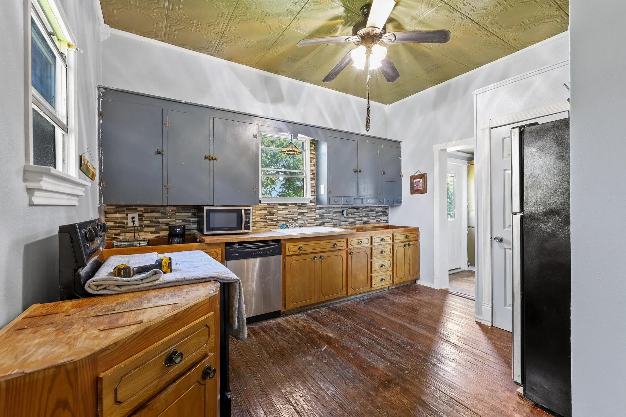 Kitchen featuring wood-finish flooring, a textured ceiling, dual windows, and a combination of upper and lower cabinetry