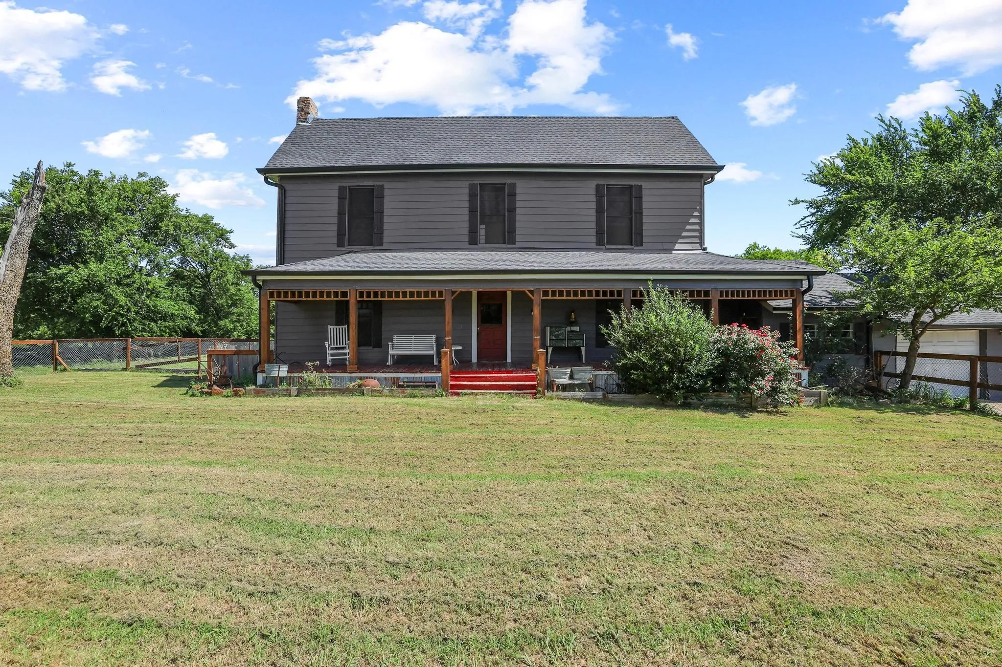 Two-story residence with a covered front porch, dark gray siding, and black window shutters