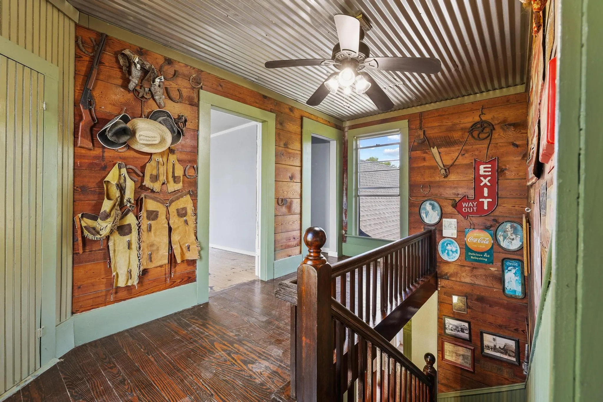 Upstairs landing are with wood-paneled hallway featuring dark wood-finish flooring, a corrugated metal ceiling, and a dark wood banister