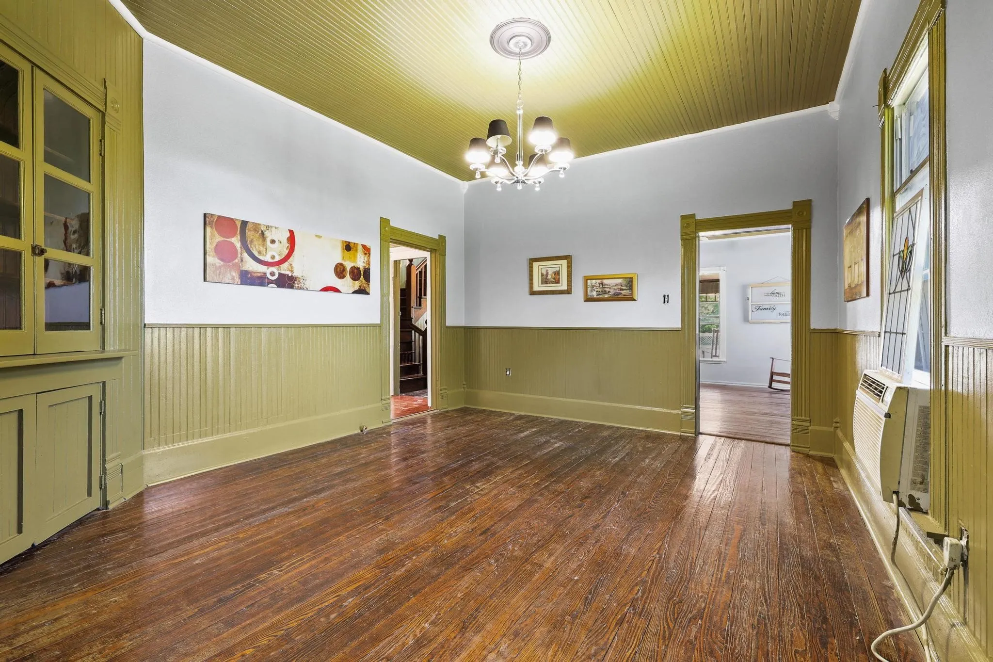 Spacious interior with rich wood flooring, beadboard wainscoting, and a built-in corner cabinet