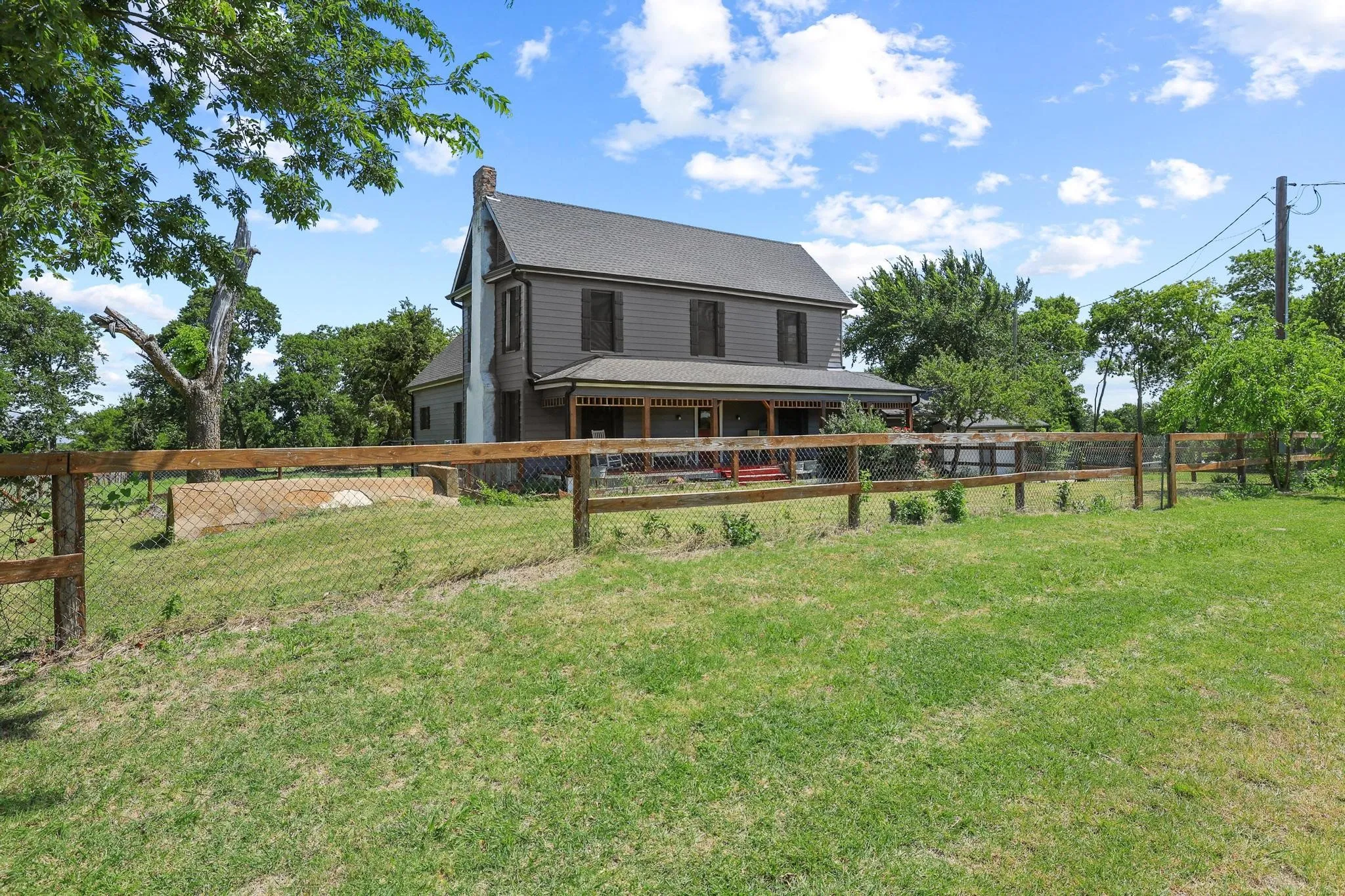 Two-story residence featuring a gray exterior, dark roof, and a prominent chimney structure