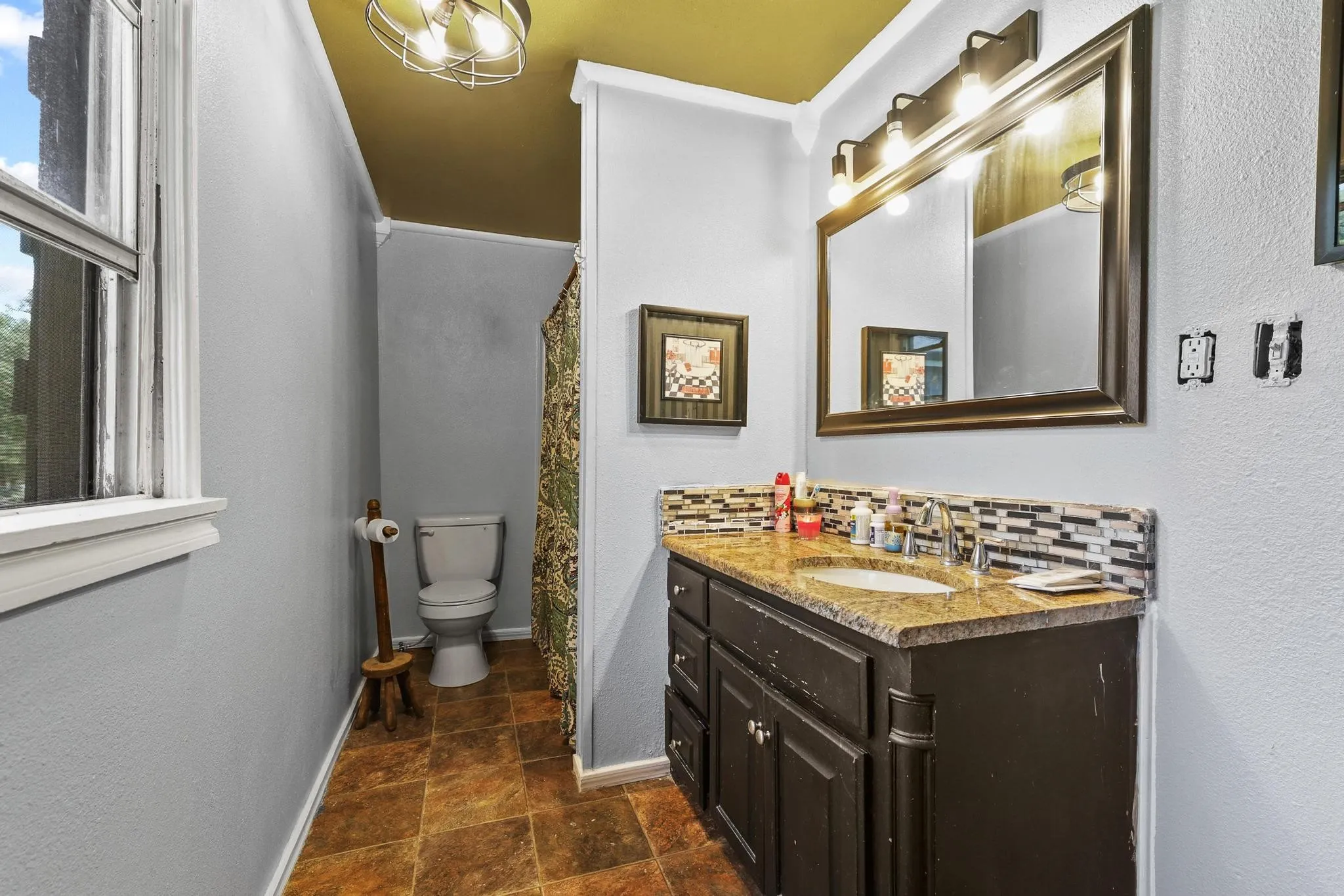 Bathroom featuring a vanity with an undermount sink, granite-style countertop, and mosaic tile backsplash