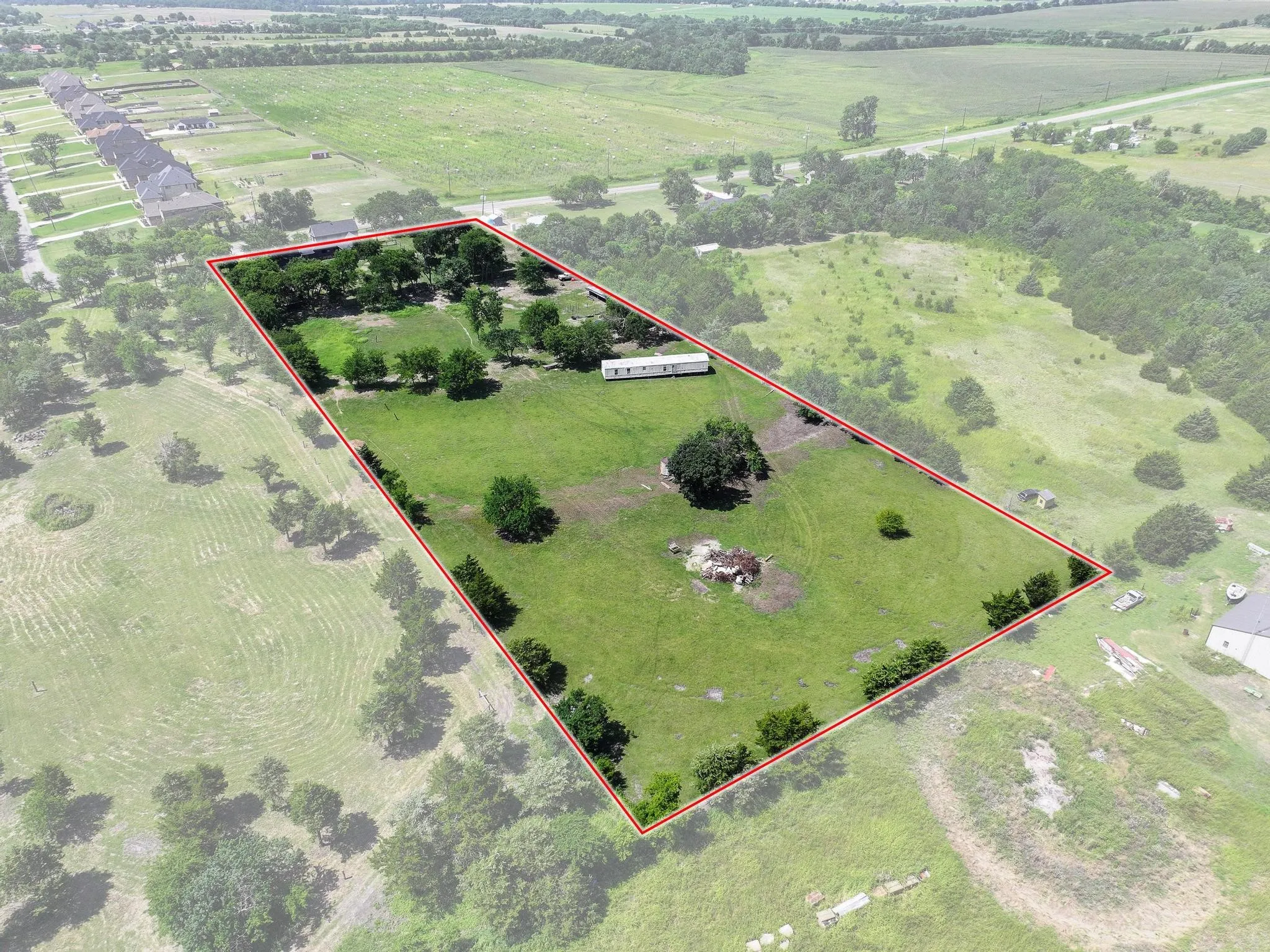 Expansive land parcel featuring a green landscape, mature trees, and a clear boundary outline