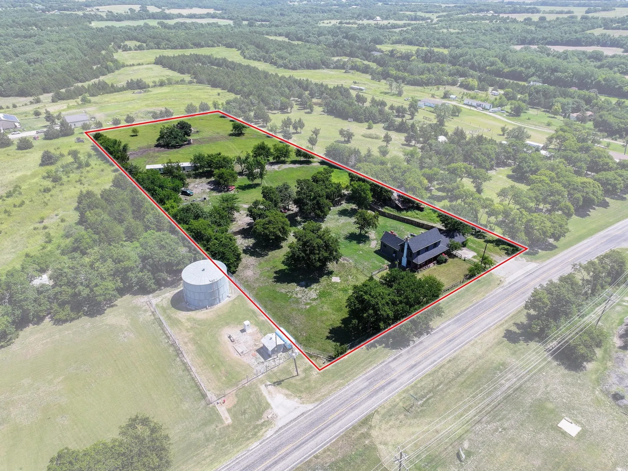 Expansive rural property featuring a single-family residence, mature trees, and open land