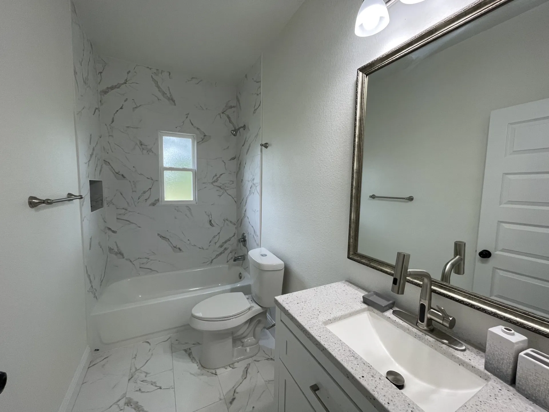 Bathroom featuring a white bathtub with a tile surround, a built-in shower niche, and a window for natural light