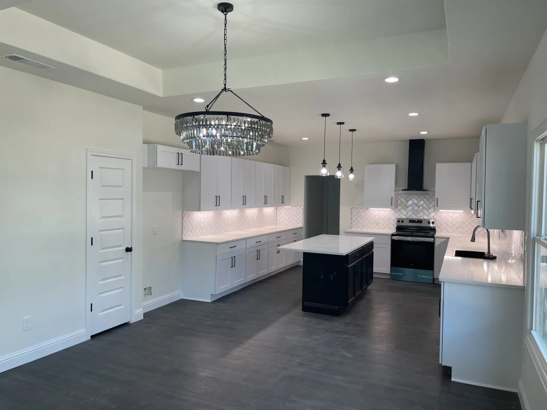 Modern kitchen featuring white cabinetry, quartz countertops, and a chevron tile backsplash