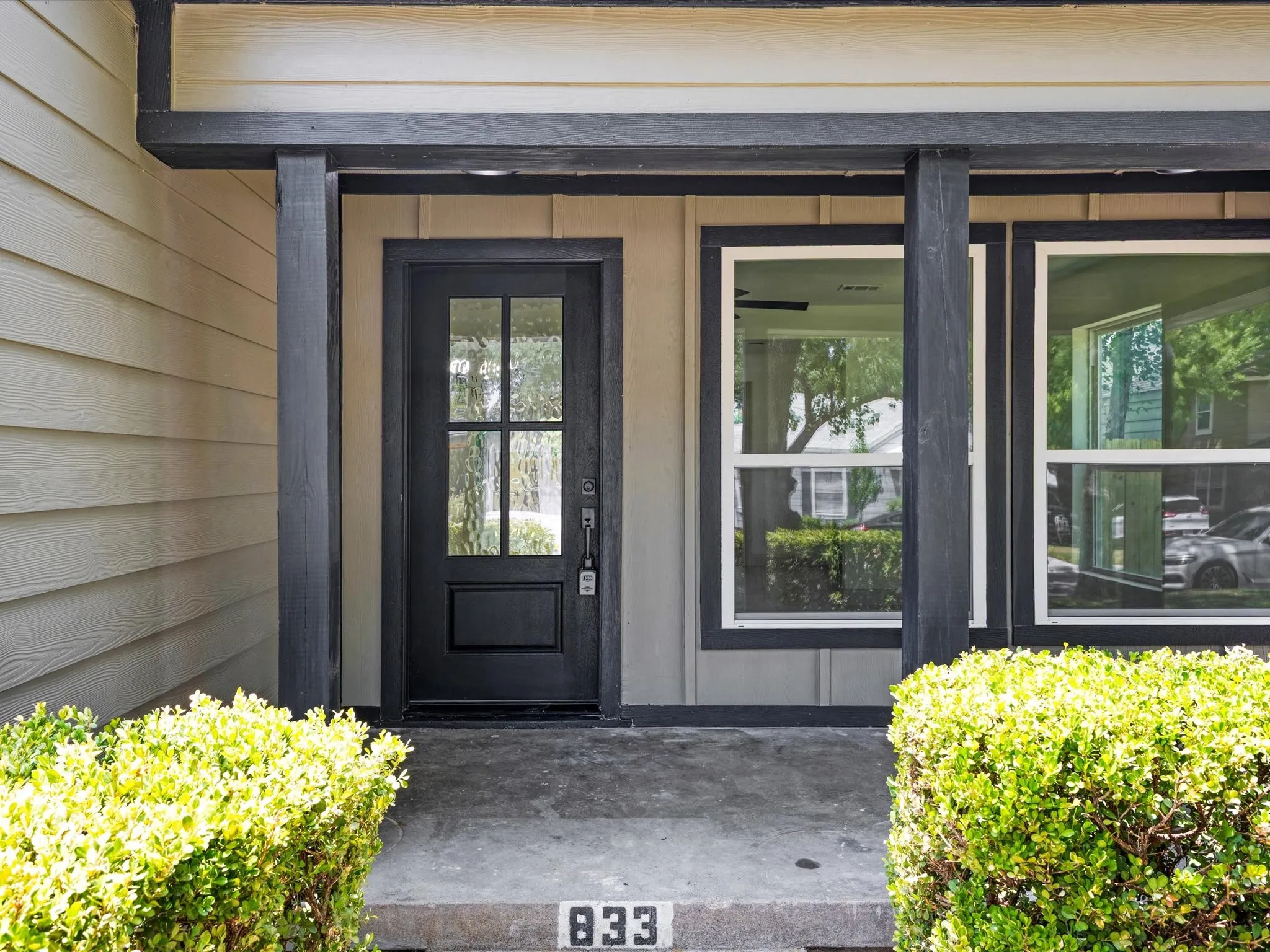 Inviting entryway featuring a dark-paneled door with glass inserts, flanked by two large windows with dark trim