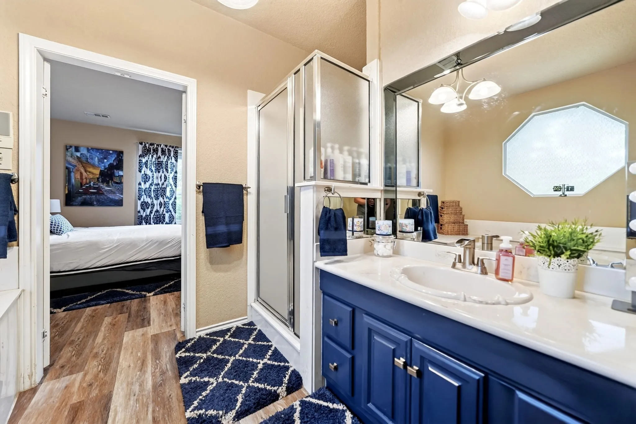 Bathroom featuring a blue vanity with an integrated sink, a large mirror, and a glass-enclosed shower