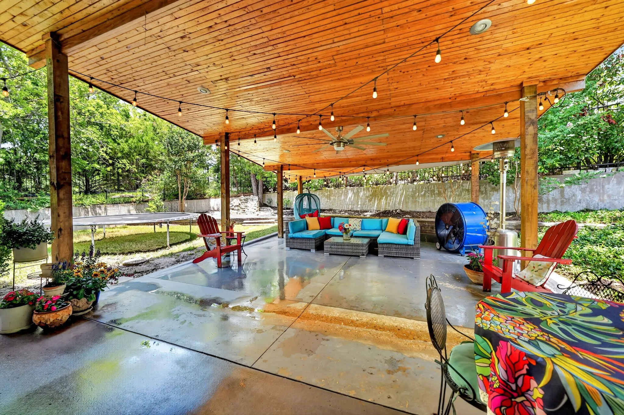Expansive covered patio featuring a wood-finish ceiling with exposed beams, string lighting, and a ceiling fan