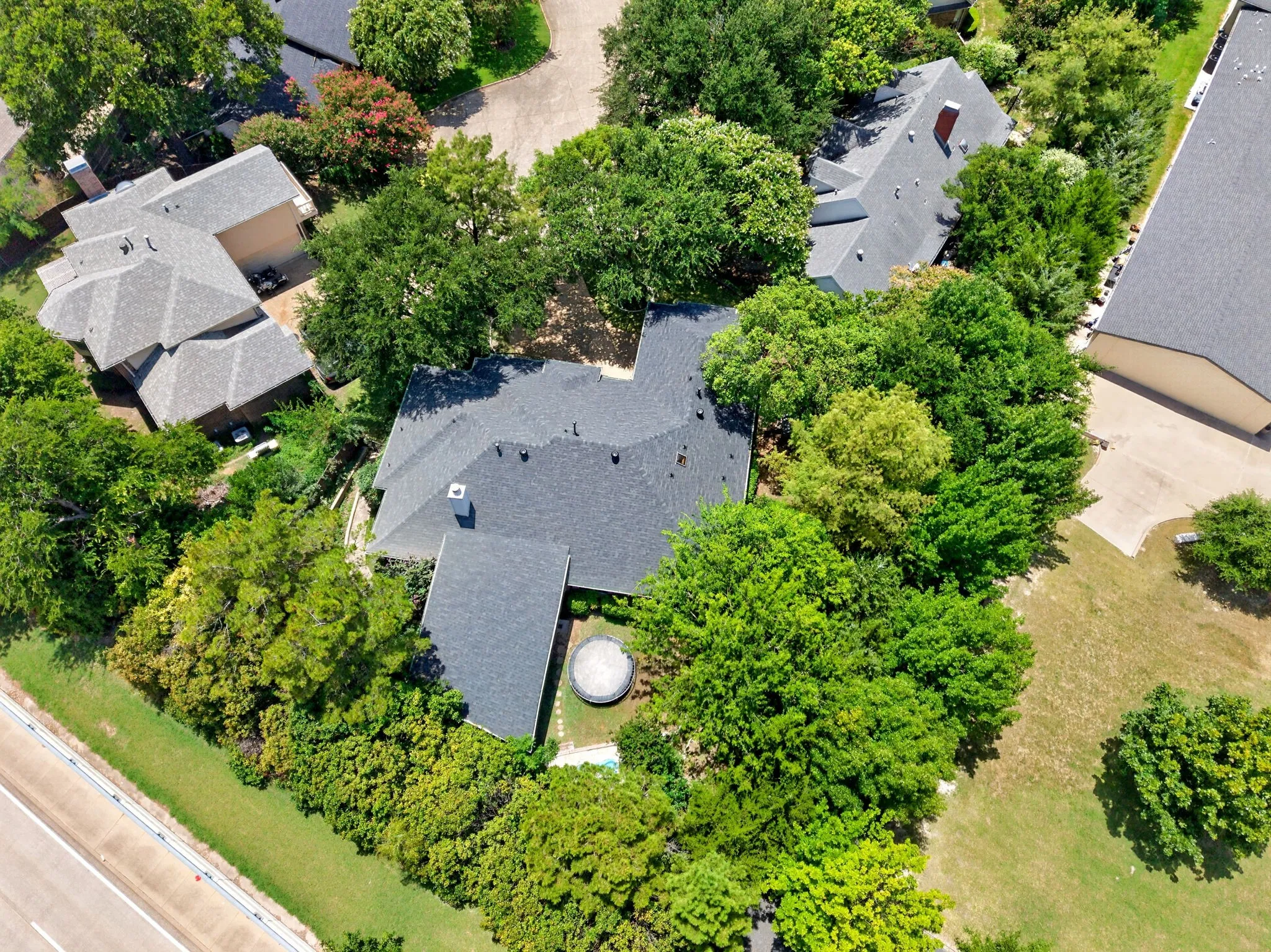 Expansive residential property featuring a dark shingle roof and a circular outdoor spa
