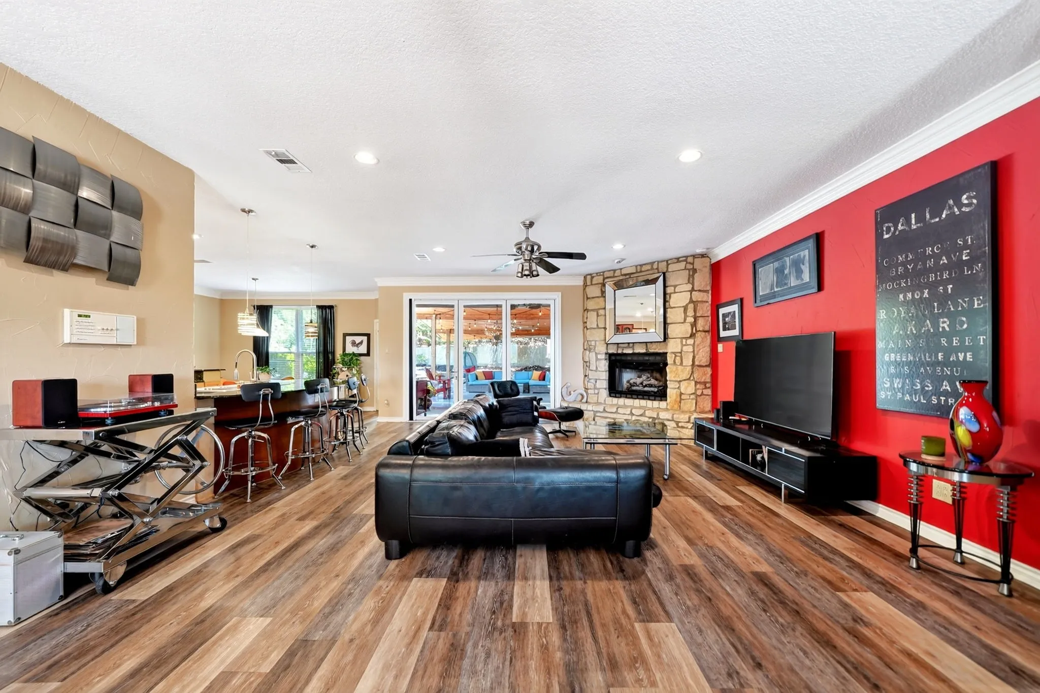 Spacious living area featuring wood-finish flooring, recessed lighting, and a stone-clad fireplace
