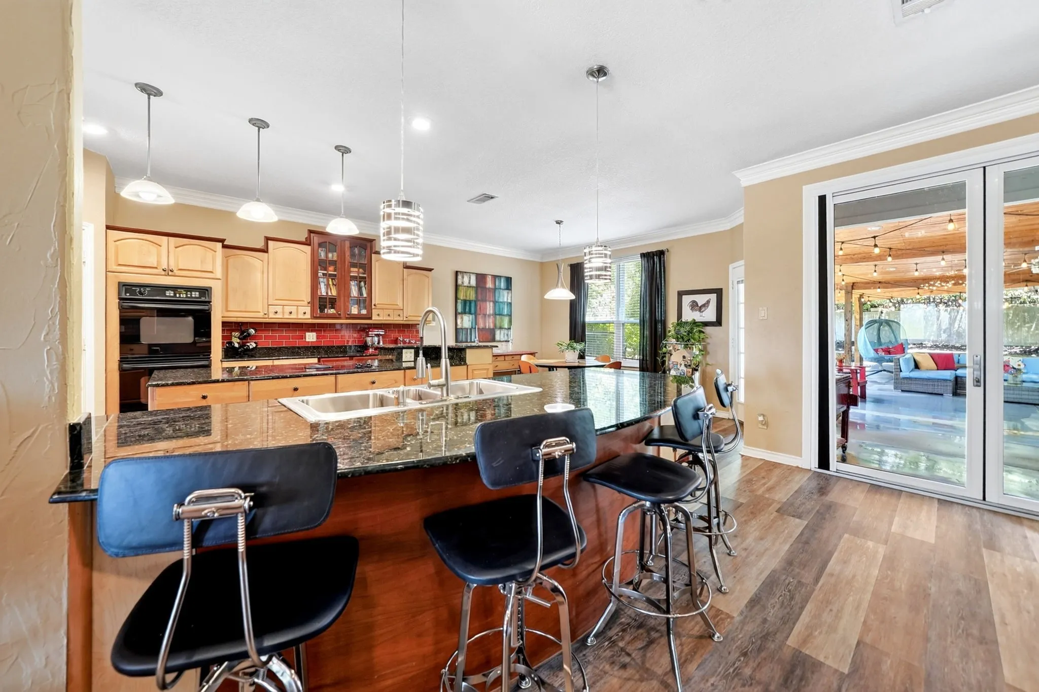 Expansive kitchen with a large island featuring a double-basin stainless steel sink and pendant lighting