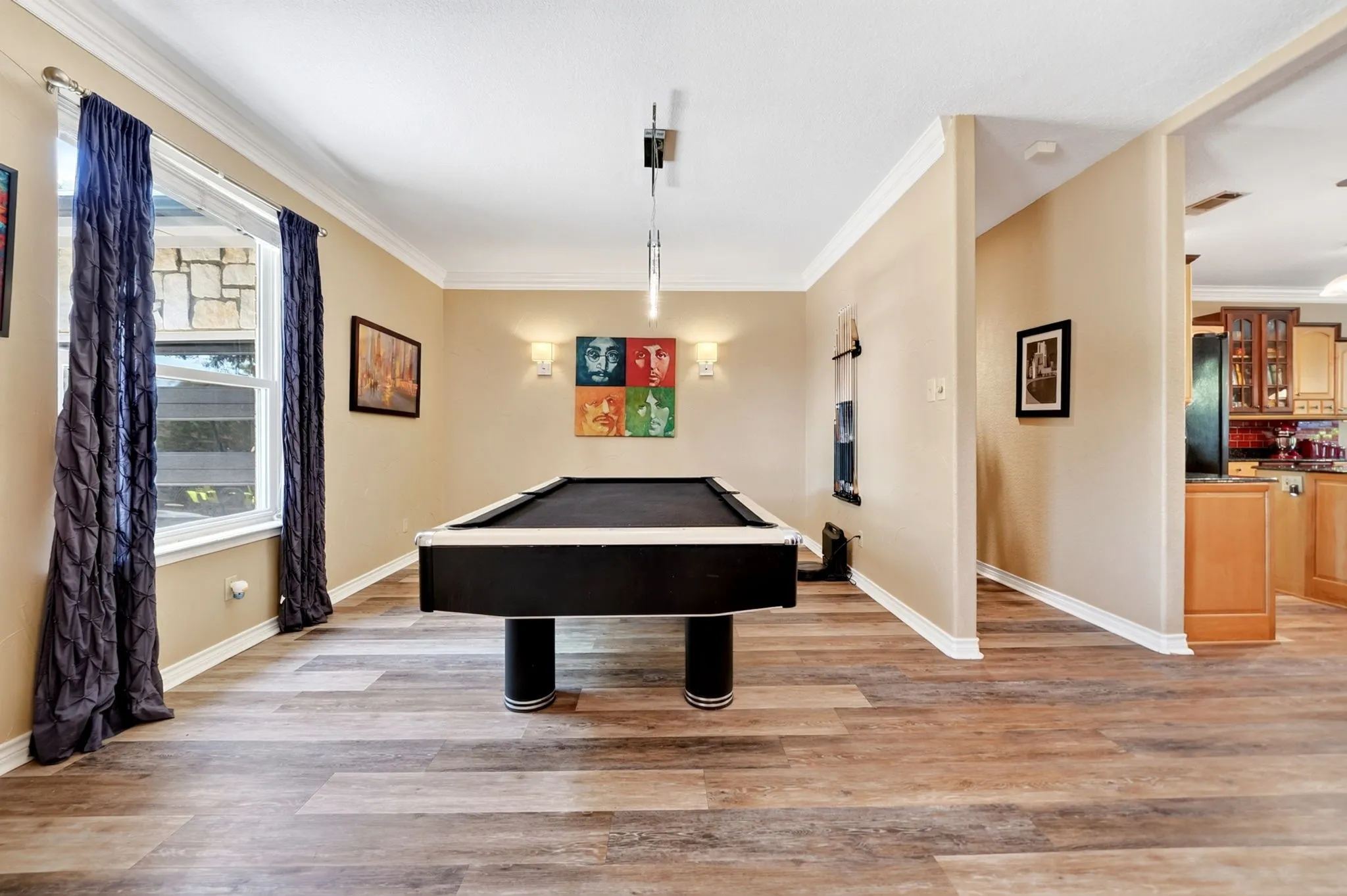Spacious room featuring wood-finish flooring, crown molding, and two windows with exterior stone detailing