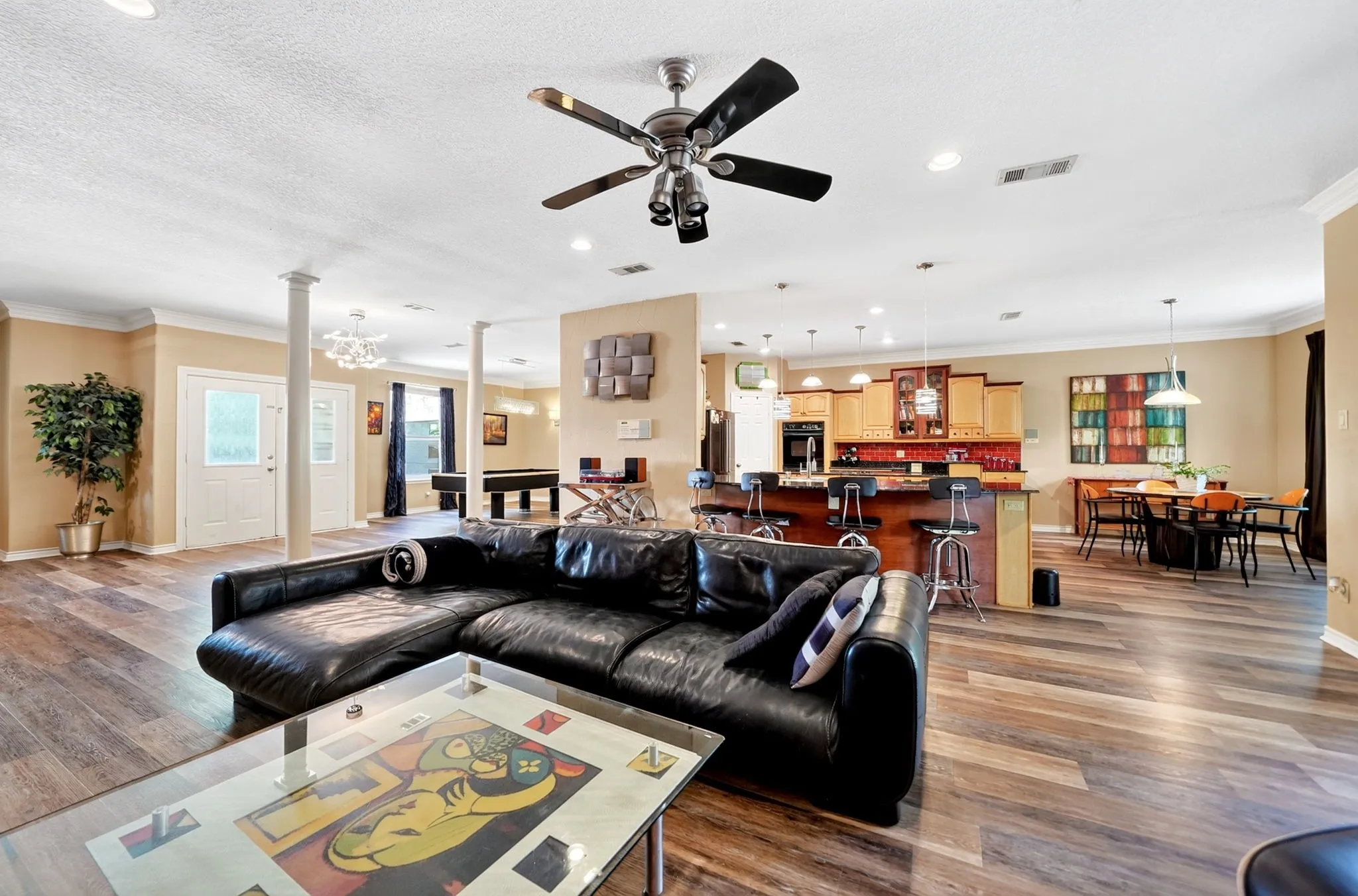 Spacious open-concept living area featuring wood-finish flooring, a ceiling fan, recessed lighting, and crown molding